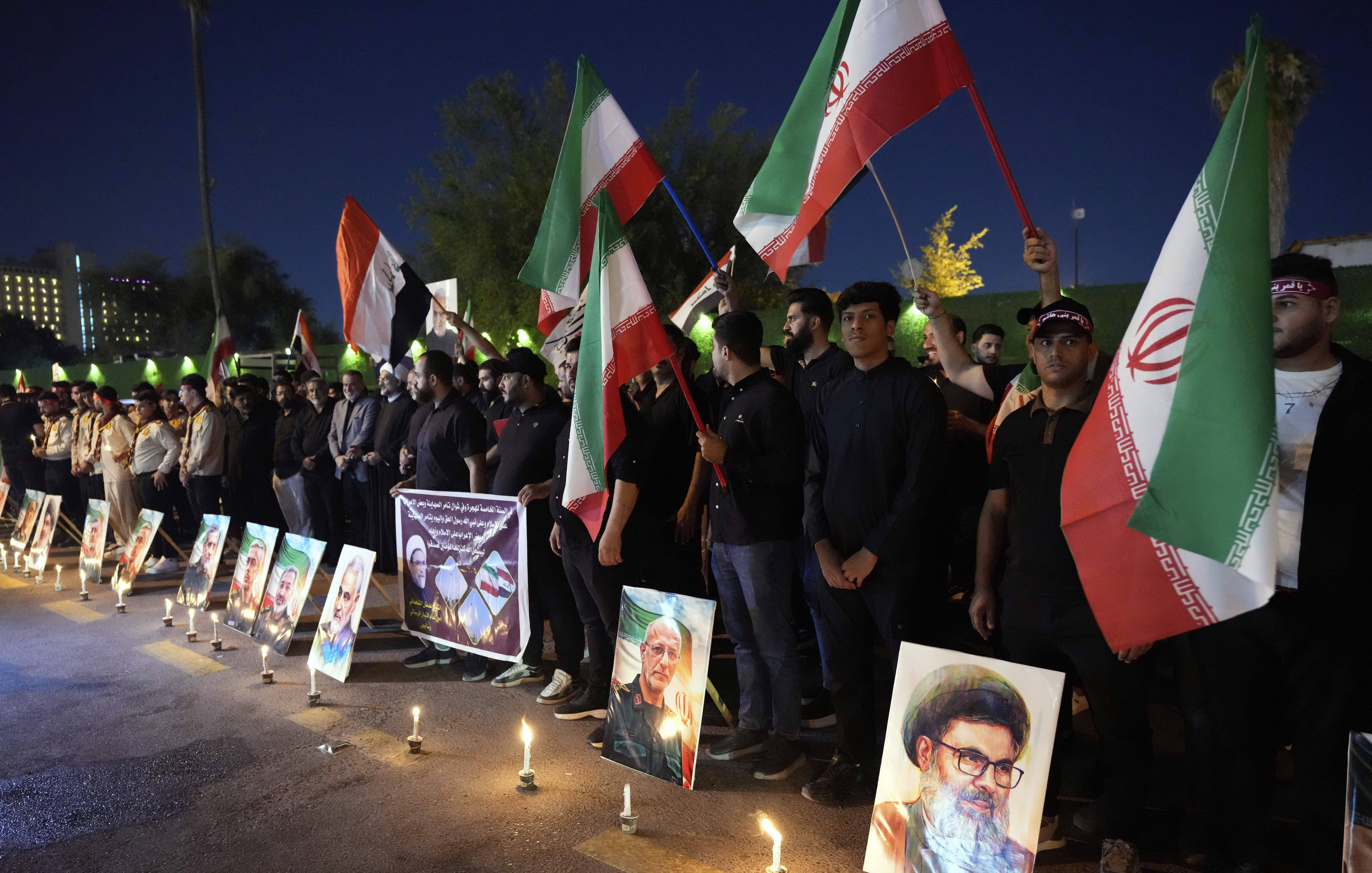 Protesters gather in front of the Iranian embassy carrying candles and Iranian flags during a stand honoring the Iranian armed forces generals, nuclear scientists, and their family members who were killed in Israeli strikes, in Baghdad, Iraq, Saturday, June 28, 2025. (AP Photo/Hadi Mizban)
