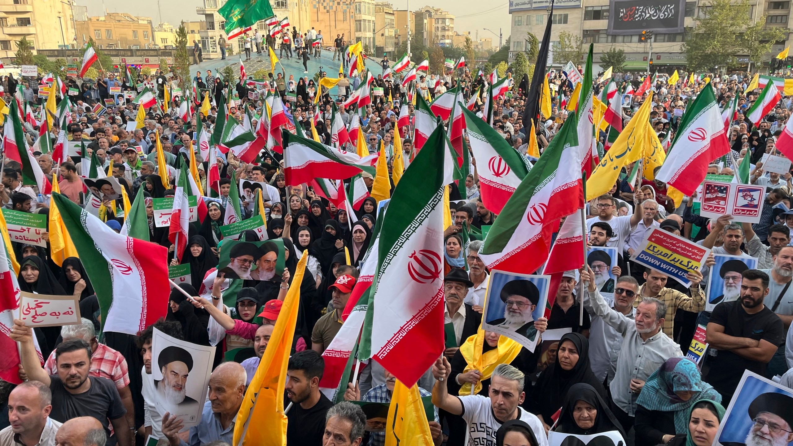 Protestors carry Iranian national flags and posters of the late revolutionary founder Ayatollah Khomeini and Supreme Leader Ayatollah Ali Khamenei, while chanting anti U.S. and Israel slogans, in Tehran, Iran, Tuesday, June 24, 2025. (AP Photo/Vahid Salemi)