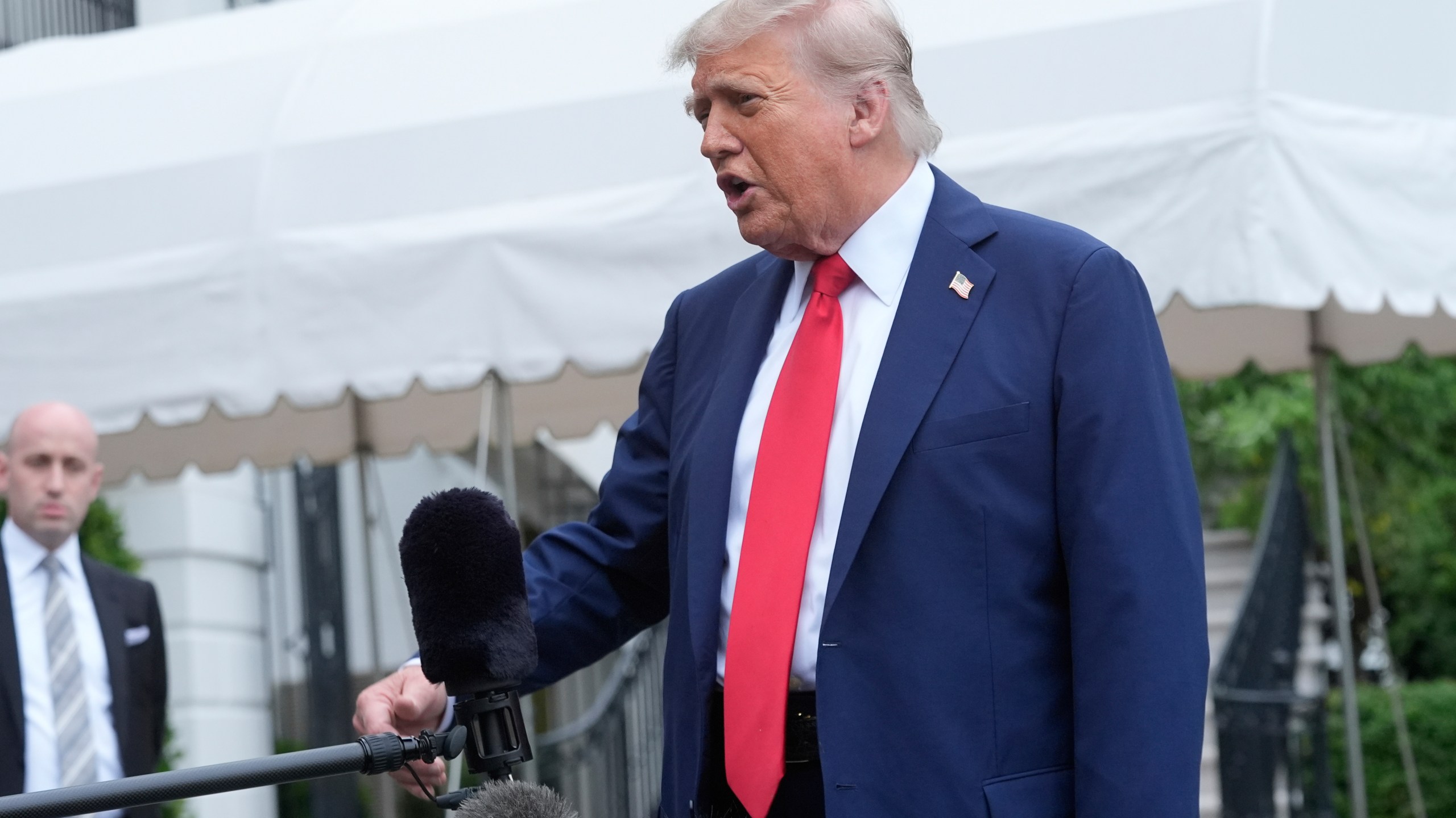 President Donald Trump speaks with reporters as White House Deputy Chief of Staff Stephen Miller listens before departing the White House on his way to attend the G7 Summit in Canada, Sunday, June 15, 2025, in Washington. (AP Photo/Manuel Balce Ceneta)