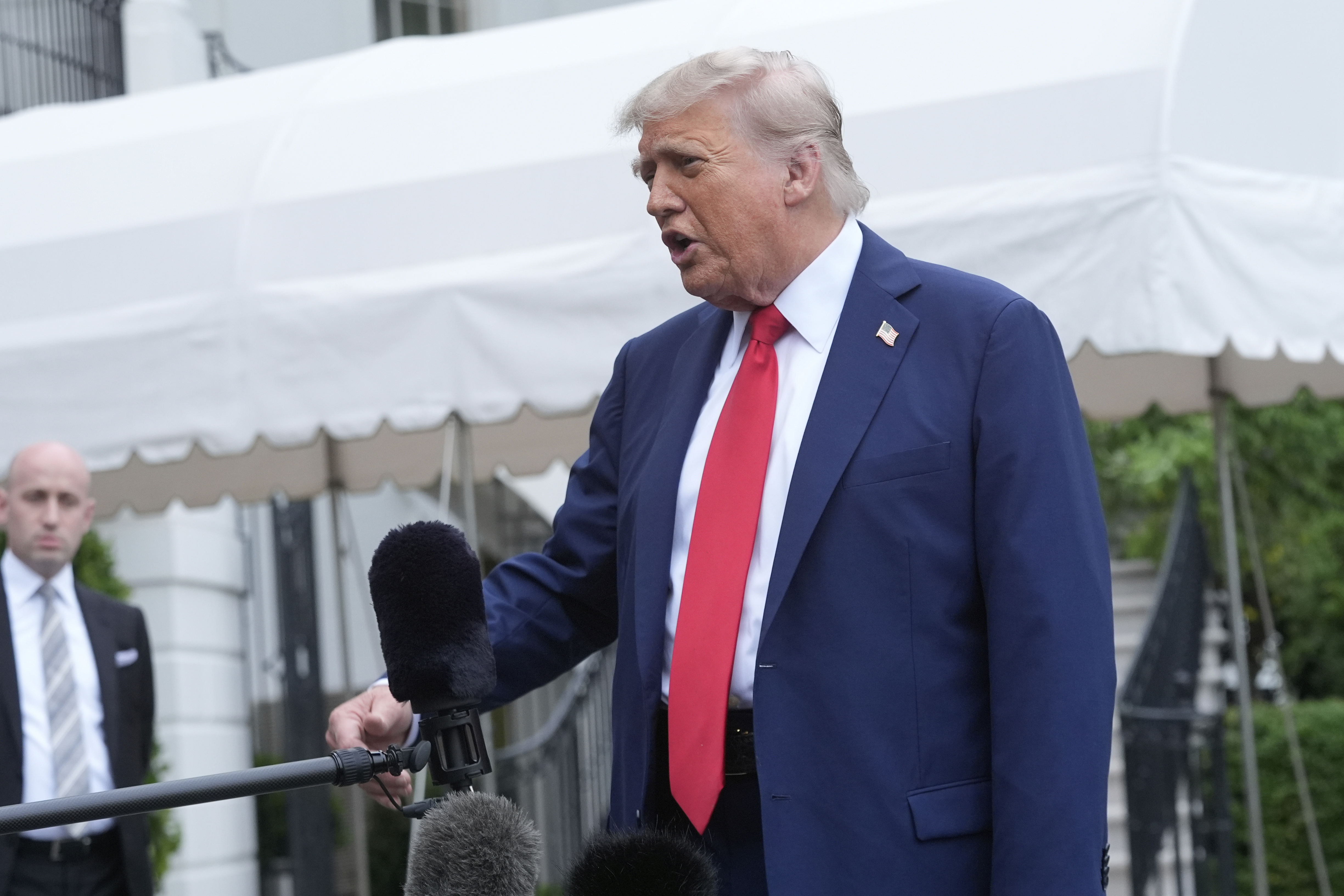 President Donald Trump speaks with reporters as White House Deputy Chief of Staff Stephen Miller listens before departing the White House on his way to attend the G7 Summit in Canada, Sunday, June 15, 2025, in Washington. (AP Photo/Manuel Balce Ceneta)