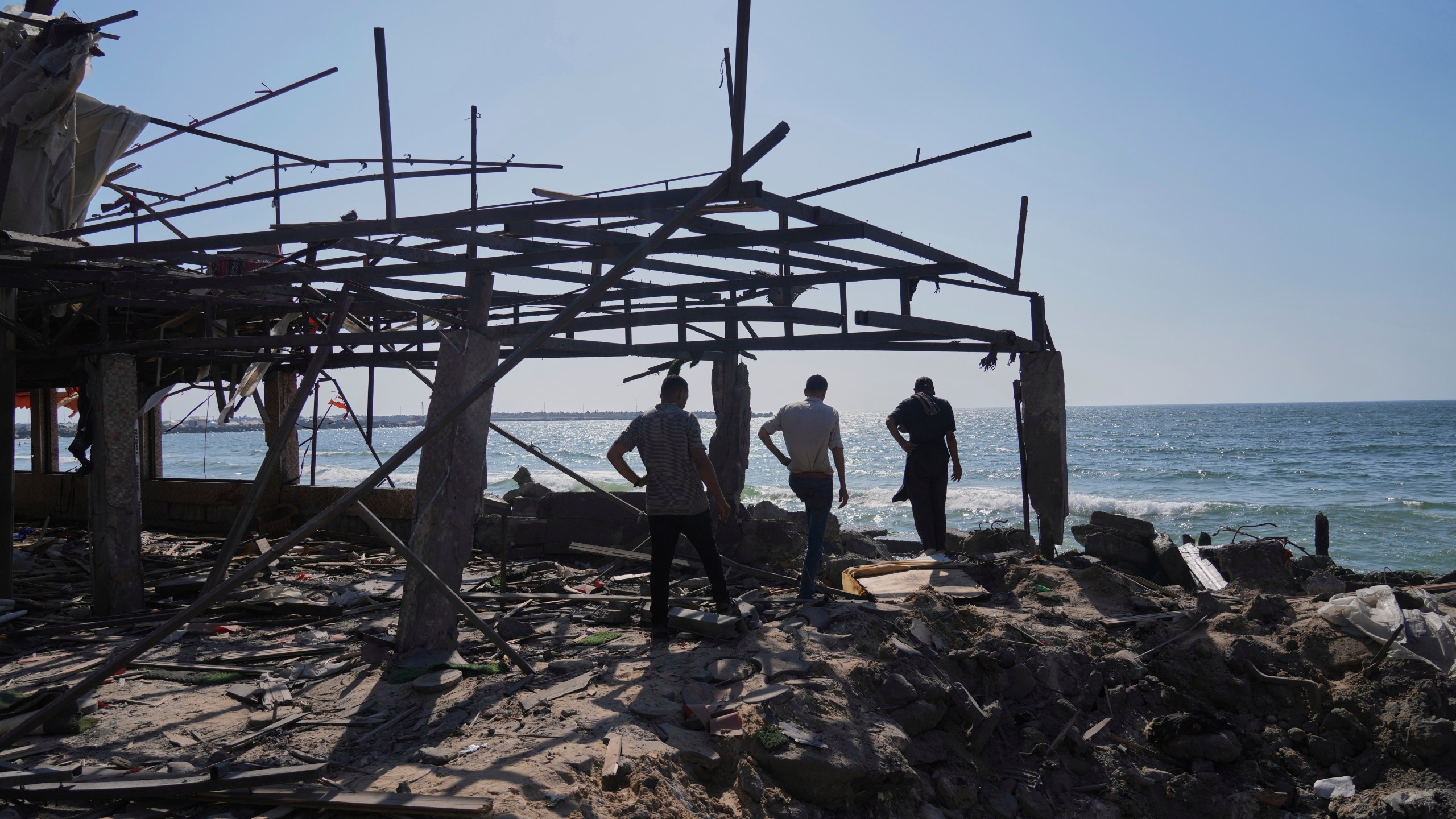 Palestinians walk in what was a cafe after it was damaged by an Israeli strike in Gaza City, Monday, June 30, 2025. (AP Photo/Jehad Alshrafi)