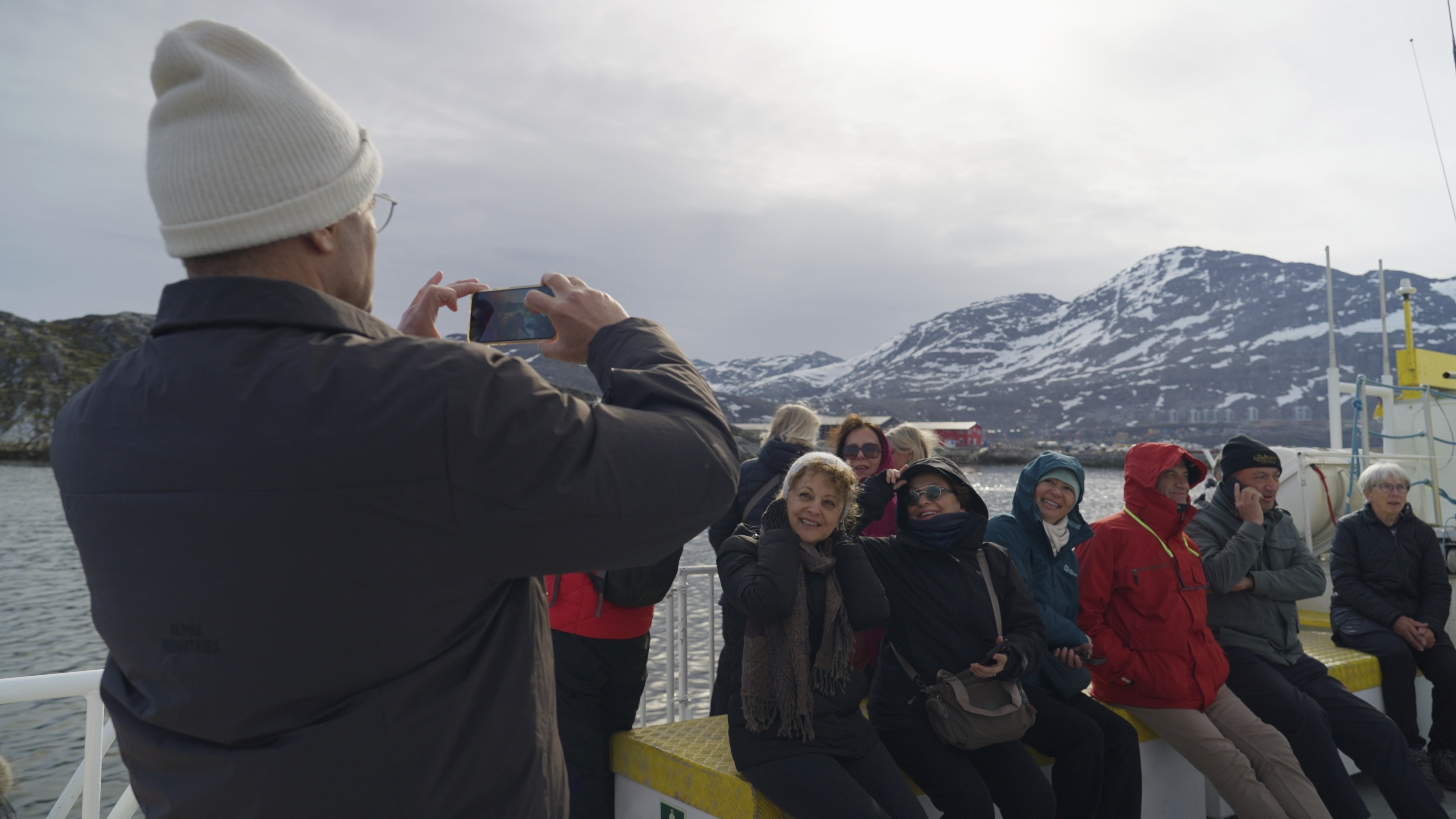 Tourists on a whale watching boat tour take photos at sea near Nuuk, Greenland, Tuesday, June 17, 2025. (AP Photo/Kwiyeon Ha)