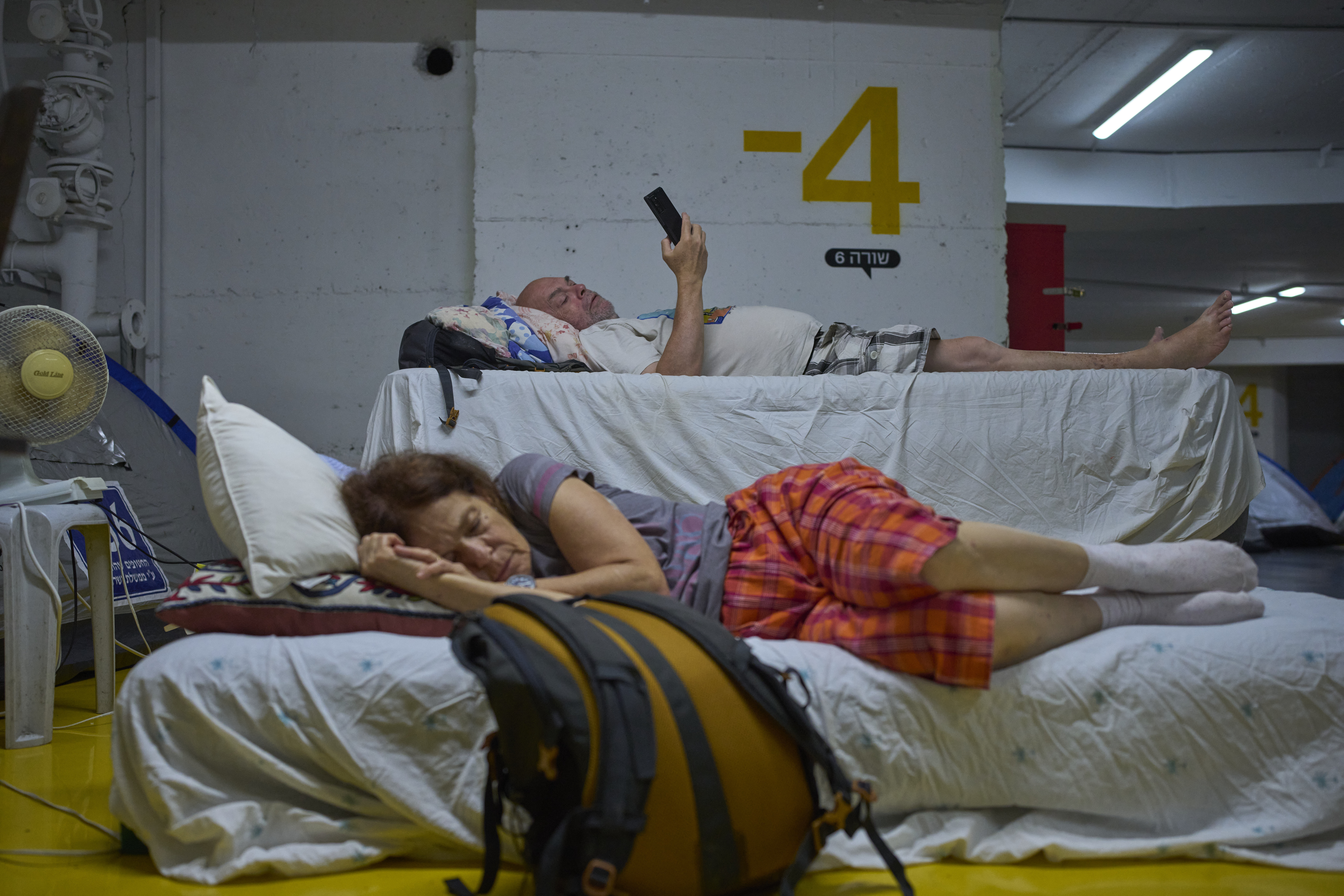 People spend the night in an underground parking garage as a precaution against possible Iranian missile attacks, in Tel Aviv, Israel, Monday, June 23, 2025. (AP Photo/Ohad Zwigenberg)