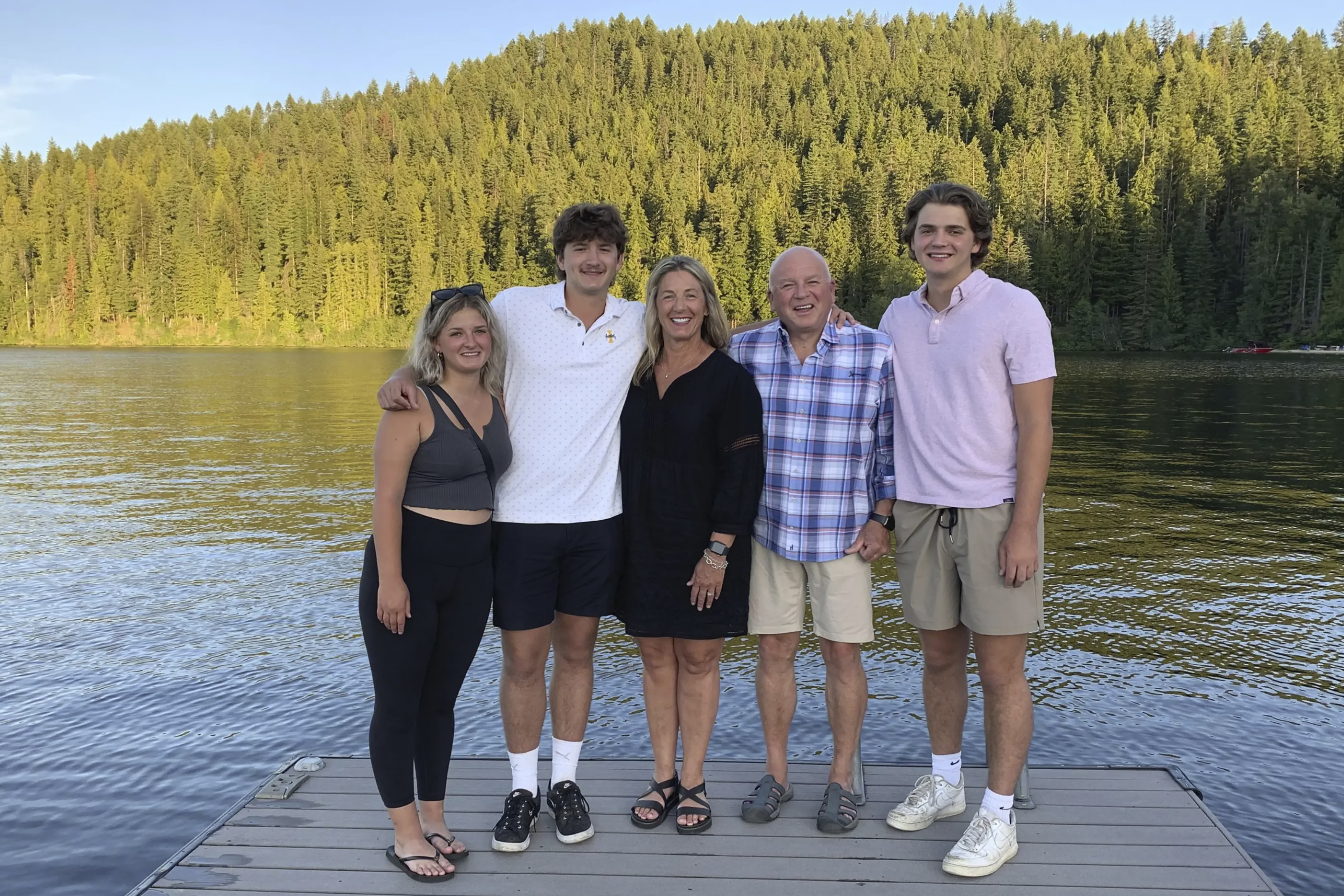 In this photo provided by Stacy Chapin, triplets Maizie, left, Ethan, second from left, and Hunter, right, pose with their parents Stacy and Jim Chapin at Priest Lake in northern Idaho in July 2022. (Stacy Chapin via AP)