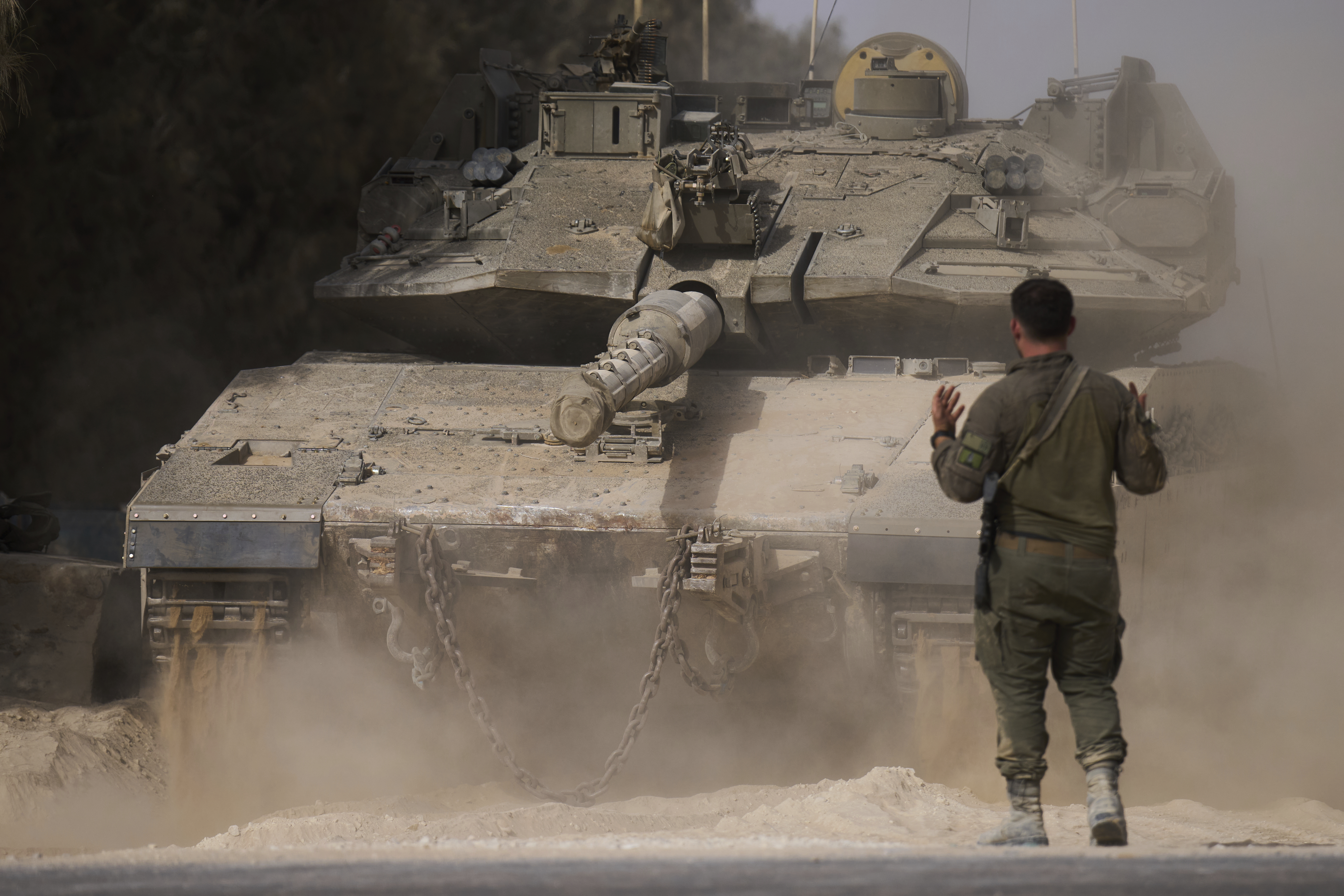 An Israeli soldier directs a tank at a staging area near the border with the Gaza Strip, in southern Israel, Tuesday, July 1, 2025. (AP Photo/Ariel Schalit)
