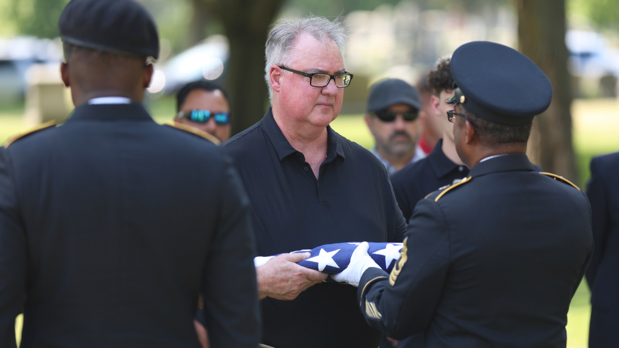 Staff Sgt. Kobe Green and Master Sgt. Derrick Bailey, right, present Mark Bailey with an American flag during during a military funeral for his aunt, 75-year-old Pfc. Reba C. Bailey, a former missing person cold case named Seven Doe, Tuesday, July 1, 2025 at Mount Olivet Catholic Cemetery in Chicago. (AP Photo/Talia Sprague)