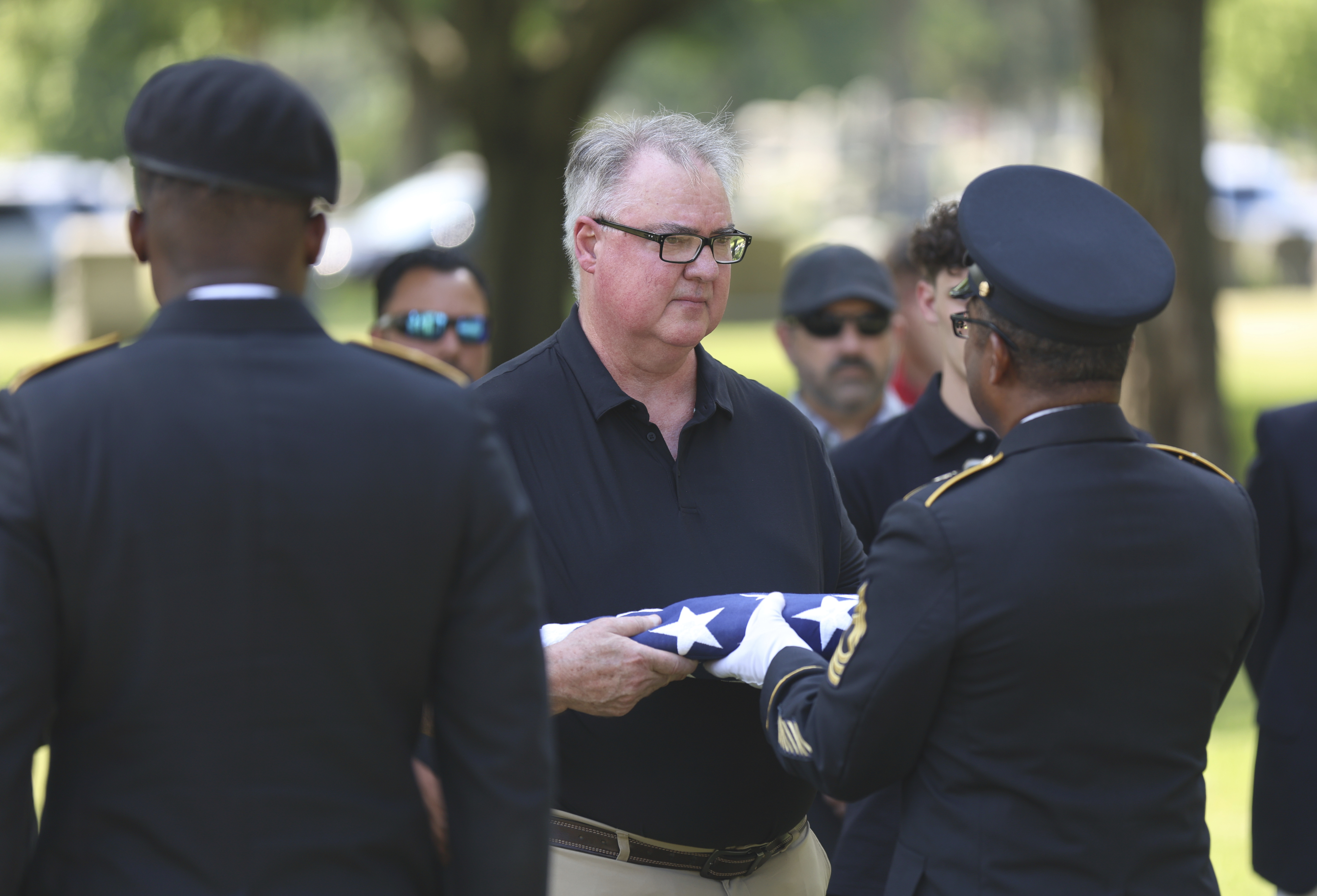 Staff Sgt. Kobe Green and Master Sgt. Derrick Bailey, right, present Mark Bailey with an American flag during during a military funeral for his aunt, 75-year-old Pfc. Reba C. Bailey, a former missing person cold case named Seven Doe, Tuesday, July 1, 2025 at Mount Olivet Catholic Cemetery in Chicago. (AP Photo/Talia Sprague)
