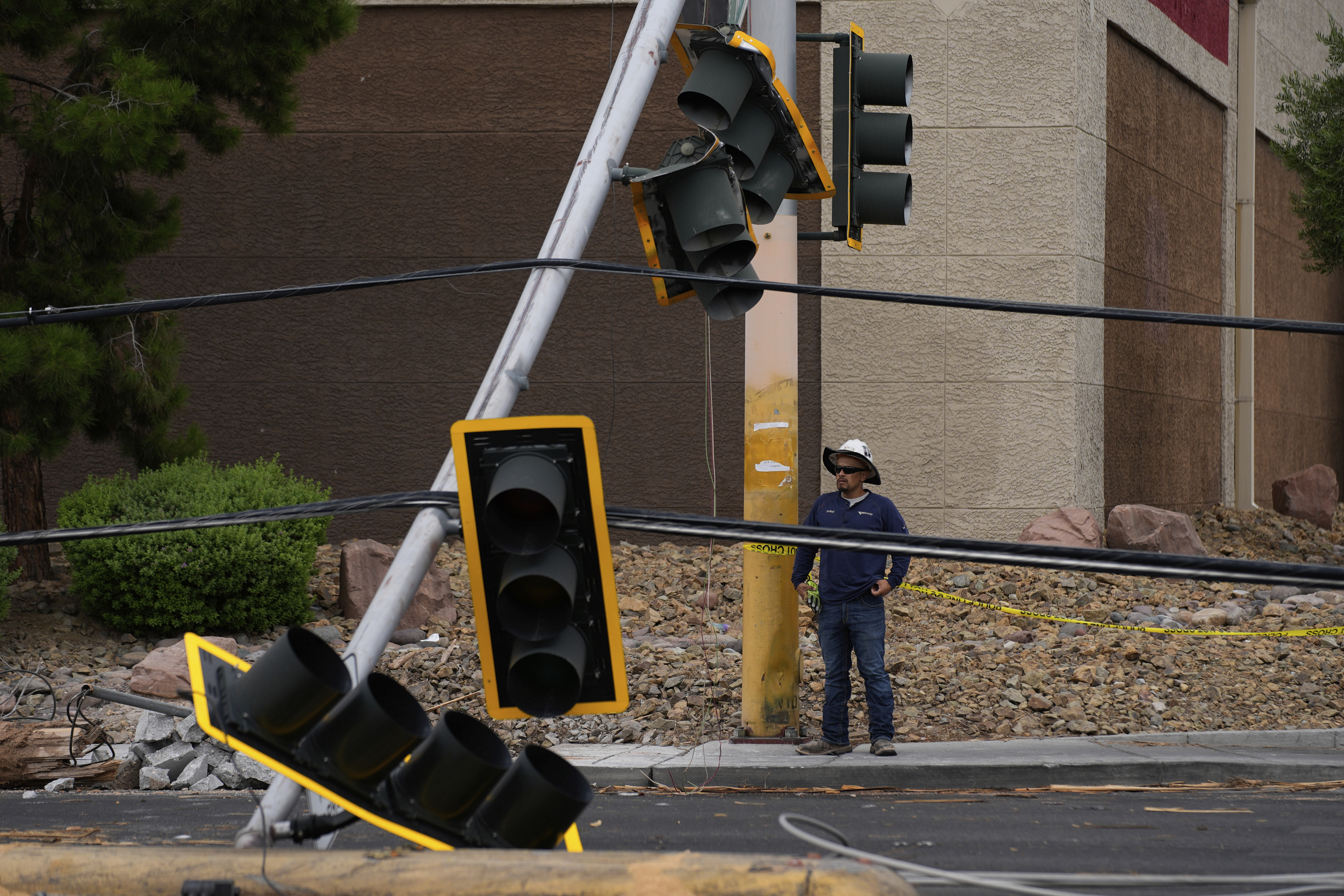 A worker stands beside traffic lights damaged in a storm Wednesday, July 2, 2025, in Las Vegas. (AP Photo/John Locher)