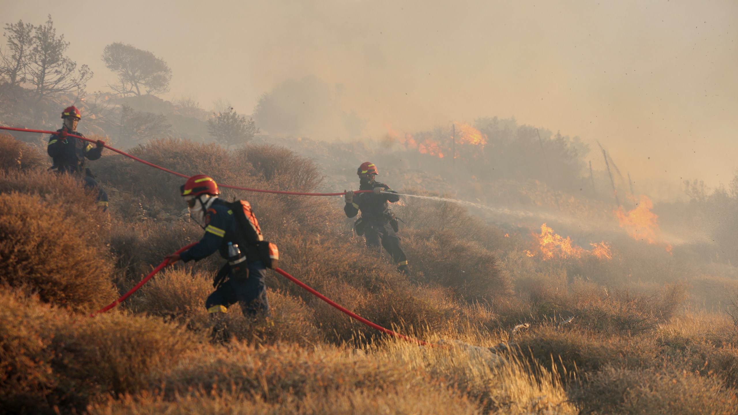 Firefighter uses a hose as the try to extinguish the blaze near the town of Ierapetra on the south coast of Crete island, Greece, Thursday July 3, 2025, as a fast-moving wildfire prompted authorities to clear villages and coastal areas, officials said. (InTime News via AP)