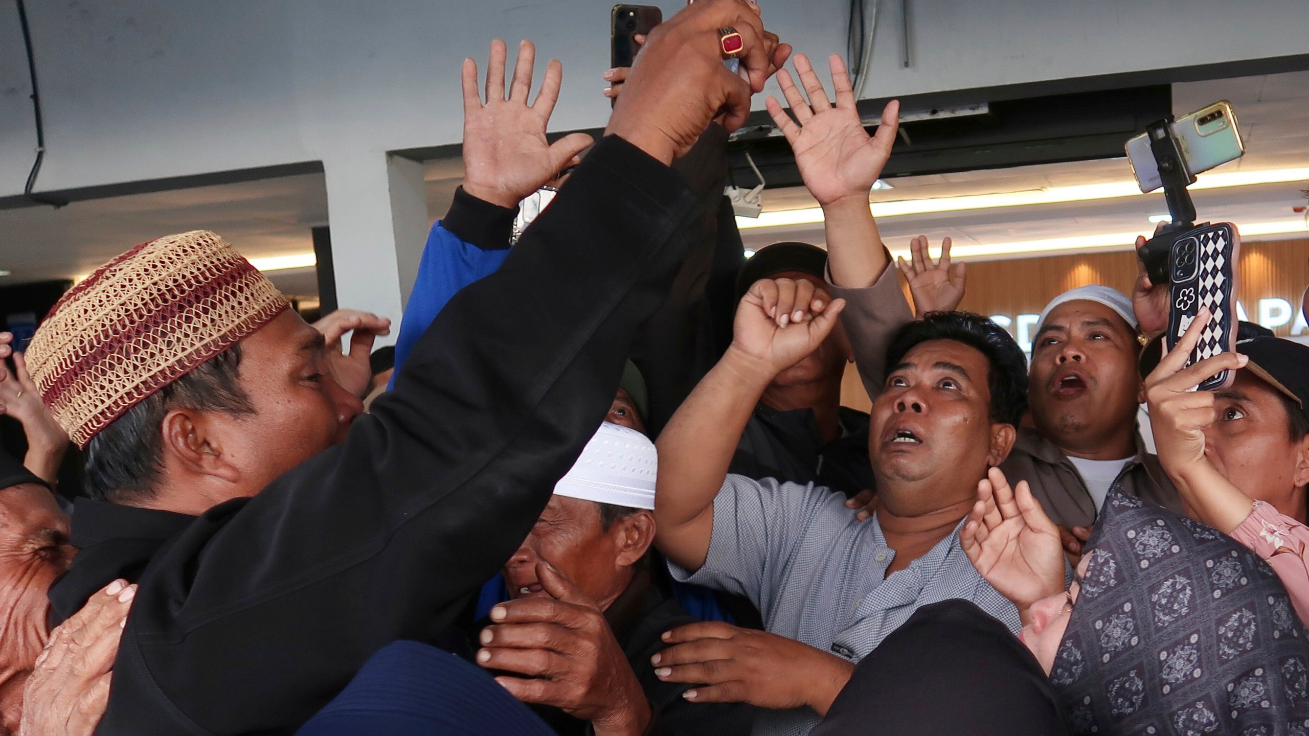 Relatives react as they have a video call with a survivor from a ferry that sank near the resort island of Bali, at Ketapang Port in Bayuwangi, East Java, Indonesia, Thursday, July 3, 2025. (AP Photo/Andur)