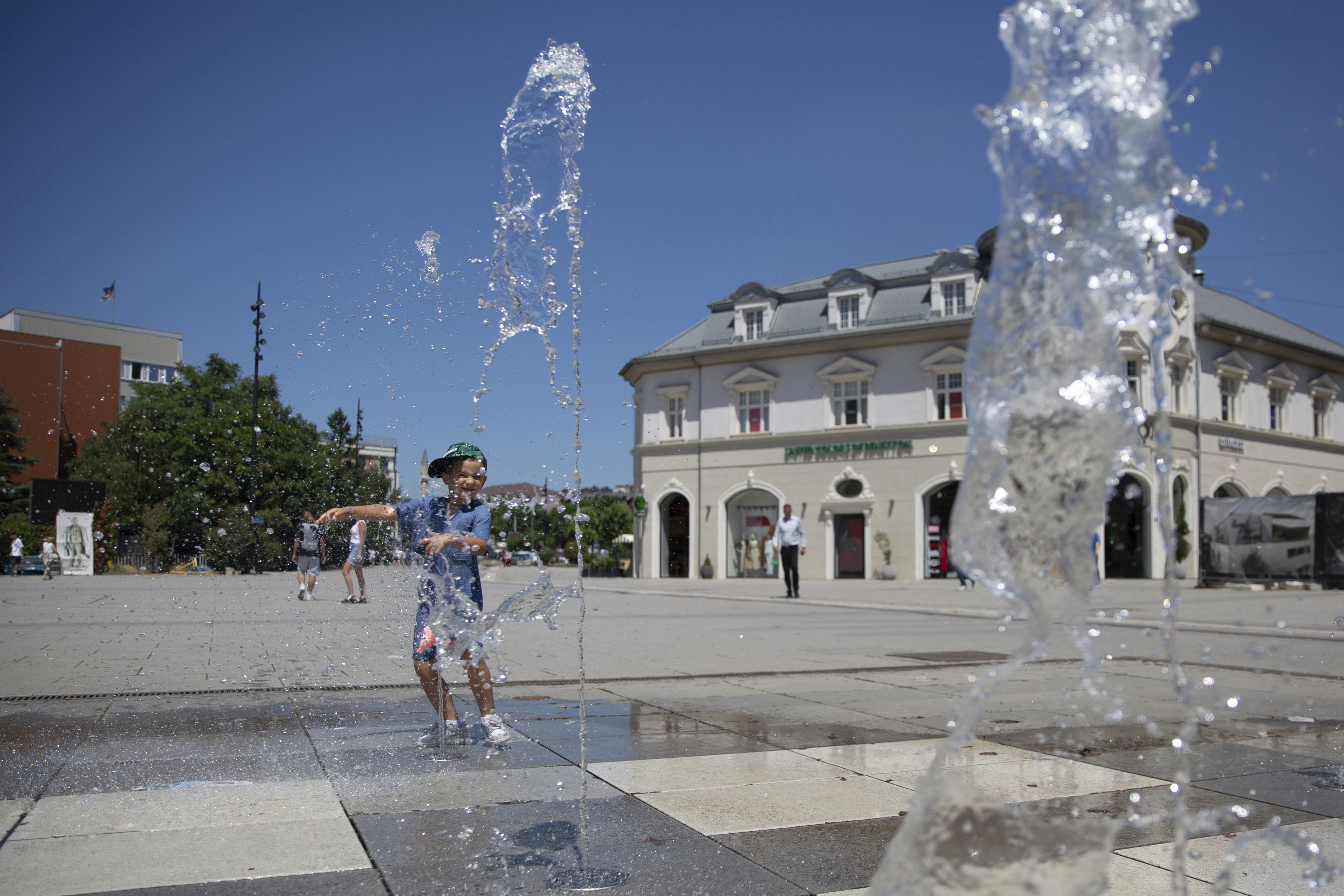 A boy plays in a fountain during hot weather in Kosovo's capital Pristina on Thursday, July 3, 2025. (AP Photo/Visar Kryeziu)