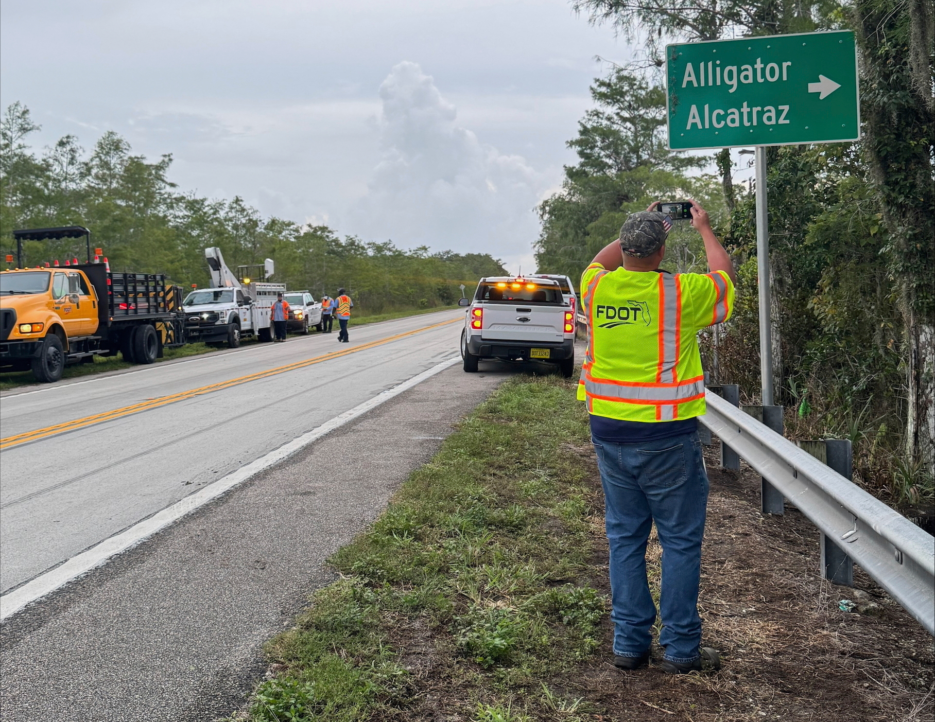 In this photo provided by Jessica Namath, a man takes a photo of a new roadside sign labeled "Alligator Alcatraz" near a new immigration detention facility in the Florida Everglades, in Ochopee, Fla. on Wednesday, July 2, 2025. (Courtesy Jessica Namath via AP)