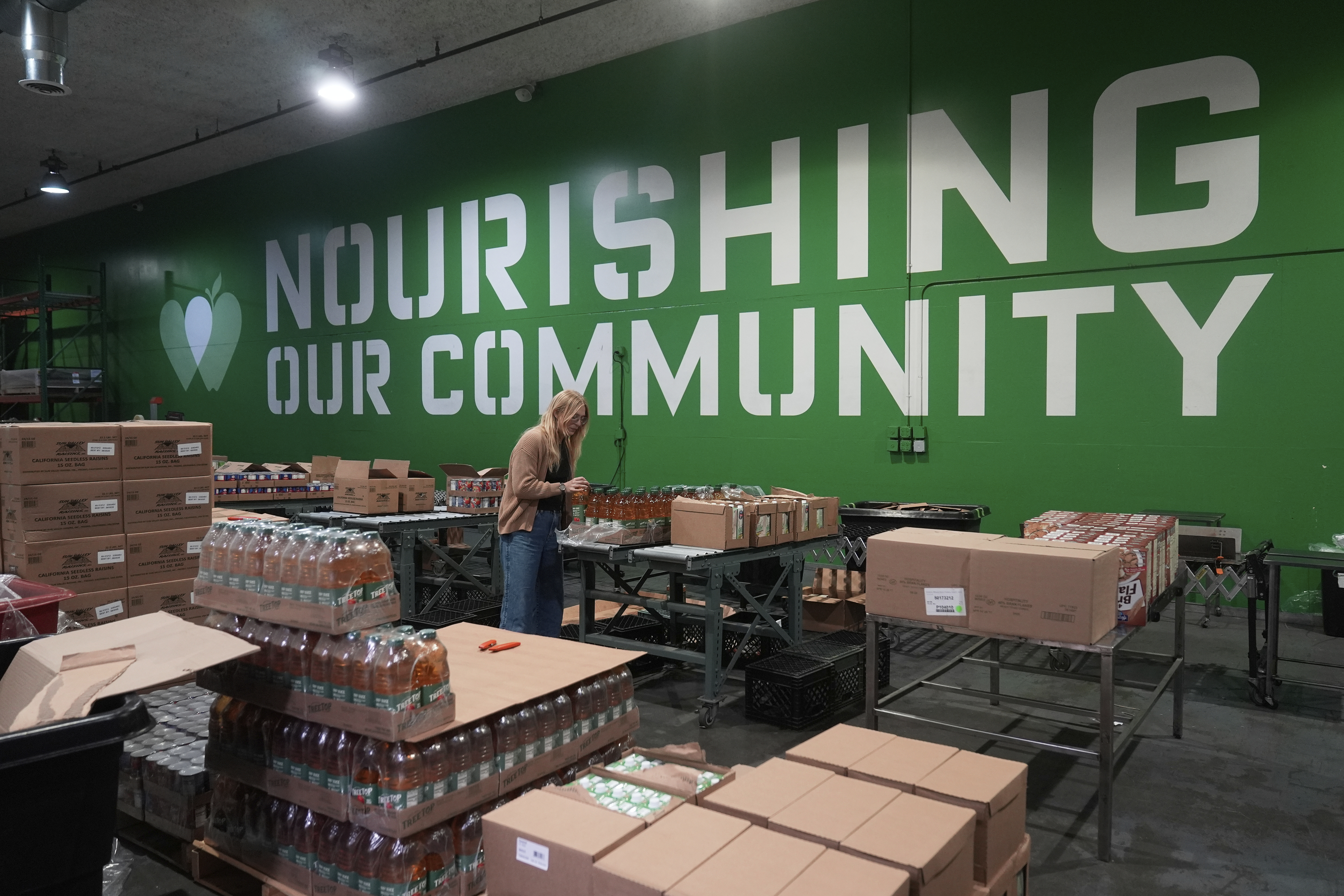 Mara Sleeter, marketing and communications project manager, stands near boxes of juice while being interviewed in the San Francisco-Marin Food Bank warehouse in San Francisco, Wednesday, July 2, 2025. (AP Photo/Jeff Chiu)