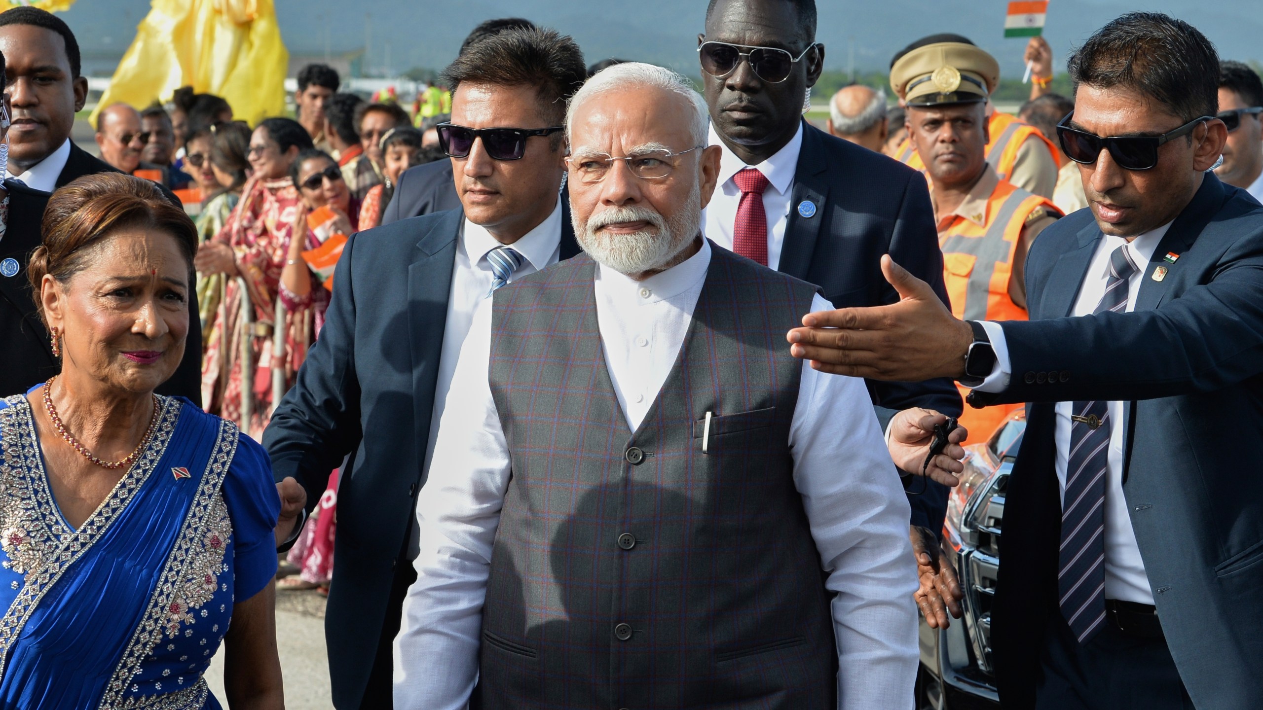 India's Prime Minister Narendra Modi, center, walks with Trinidad and Tobago Prime Minister Kamla Persad-Bissessar, dressed in traditional Indian attire, left, upon his arrival at Piarco International Airport in Piarco, Trinidad and Tobago, Thursday, July 3, 2025. (AP Photo/Jermaine Cruickshank)