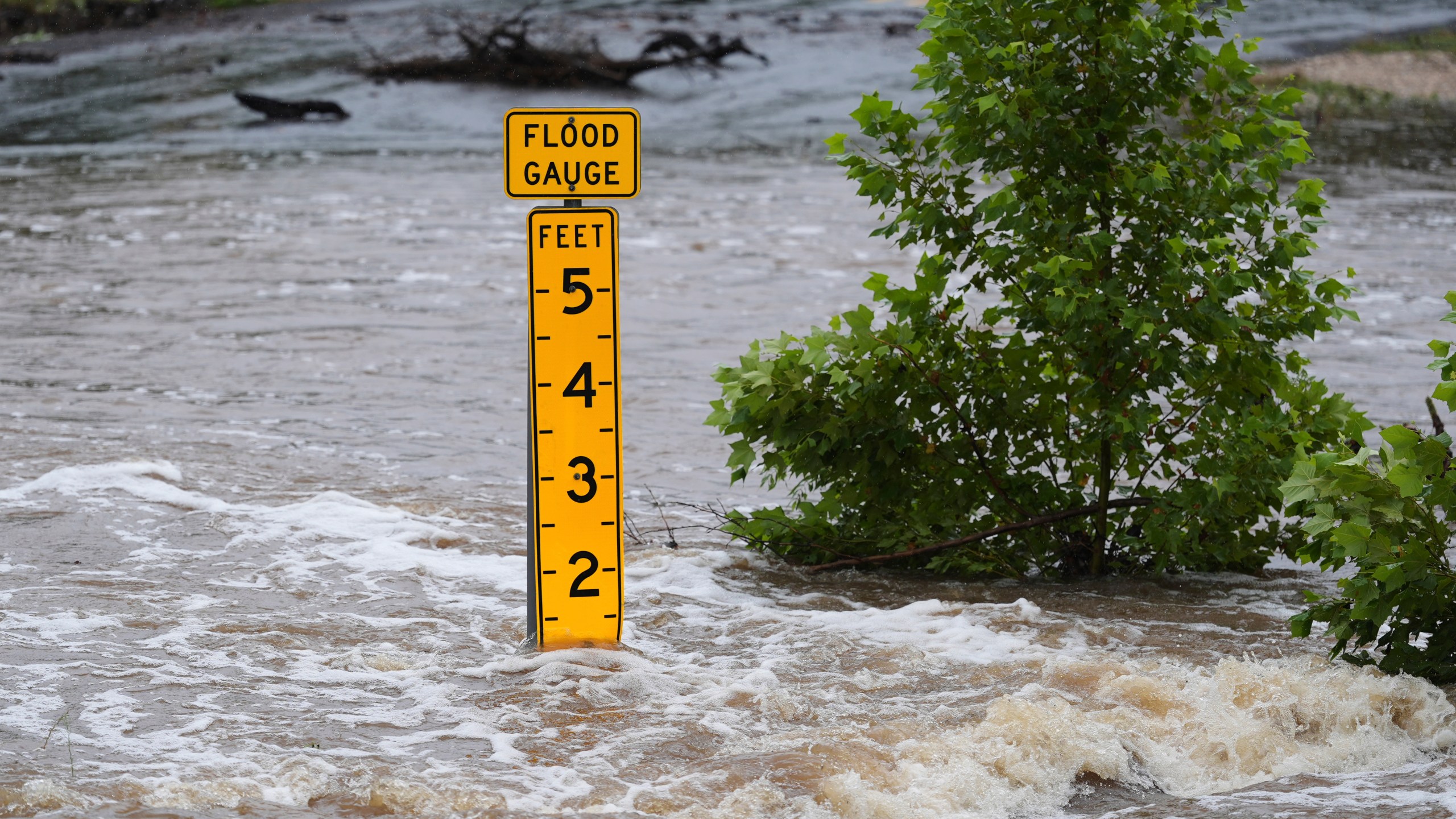 A flood gauge marks the height of water flowing over a farm-to-market road near Kerrville, Texas, on Friday, July 4, 2025. (AP Photo/Eric Gay)