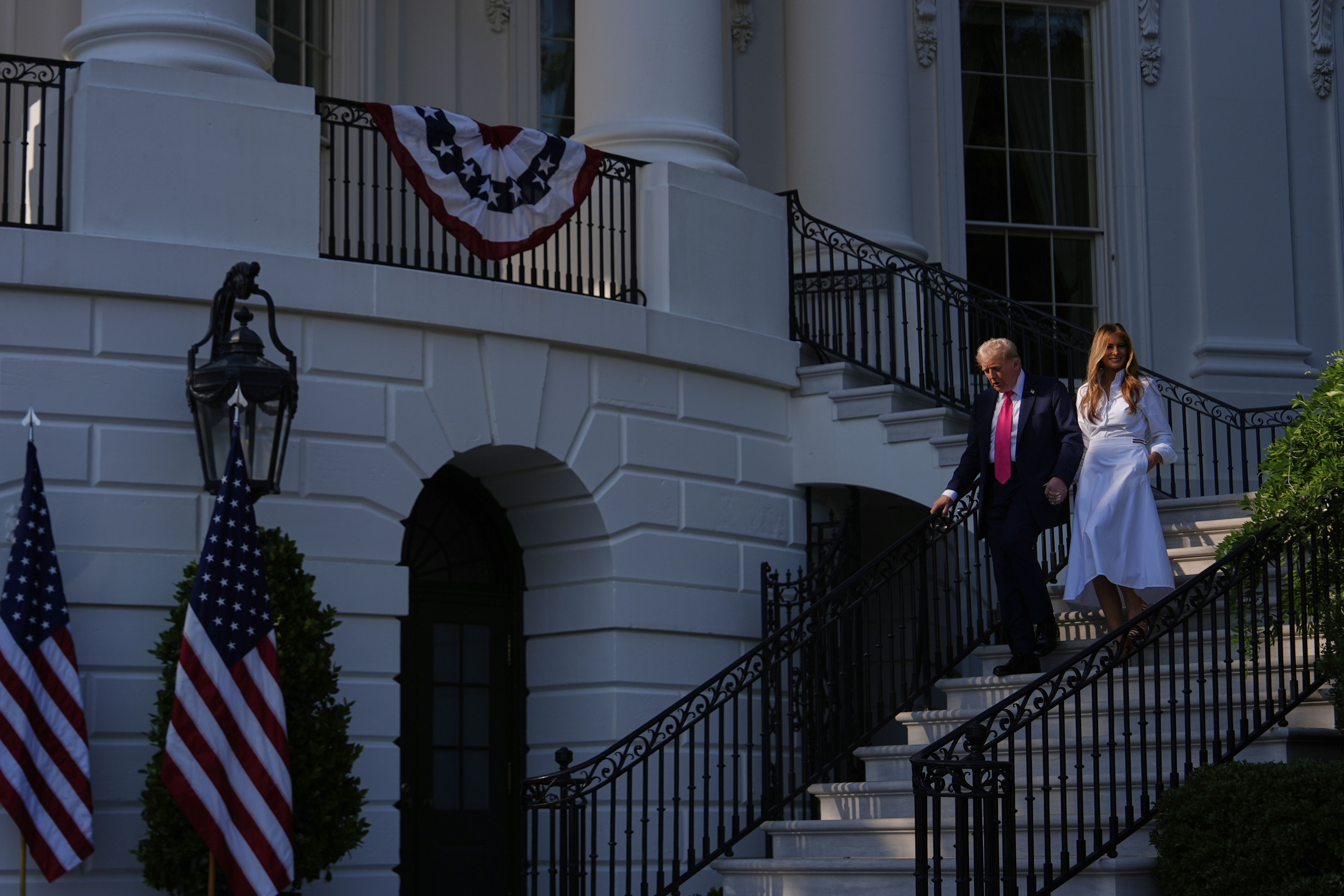 President Donald Trump and first lady Melania Trump walk down the steps from the Blue Room Balcony to sign his signature bill of tax breaks and spending cuts at the White House, Friday, July 4, 2025, in Washington. (AP Photo/Julia Demaree Nikhinson)