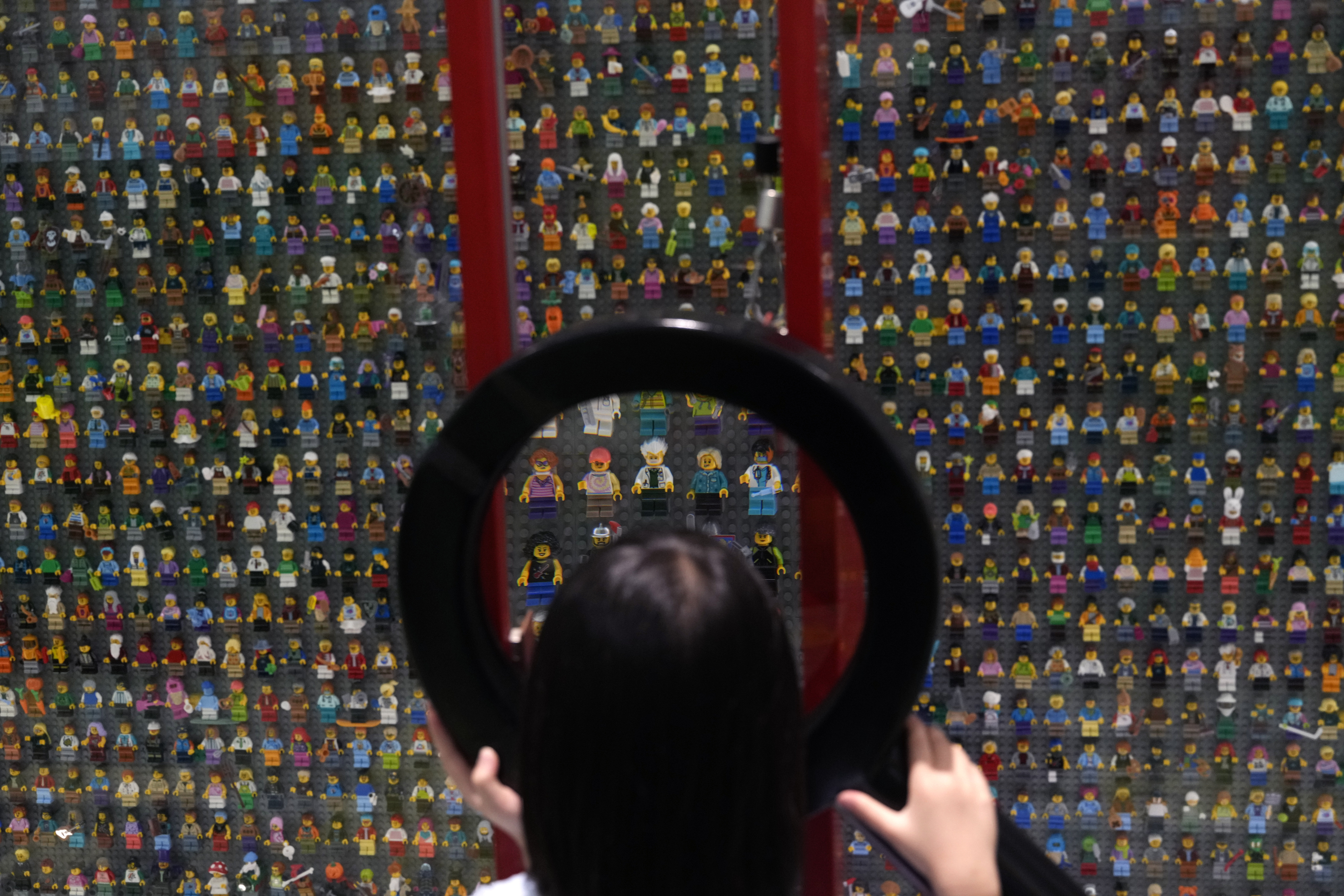 A child uses a magnifying glass to look at Lego characters at the hotel in Legoland Shanghai a day before it opens to the public in Shanghai, China, Friday, July 4, 2025. (AP Photo/Ng Han Guan)