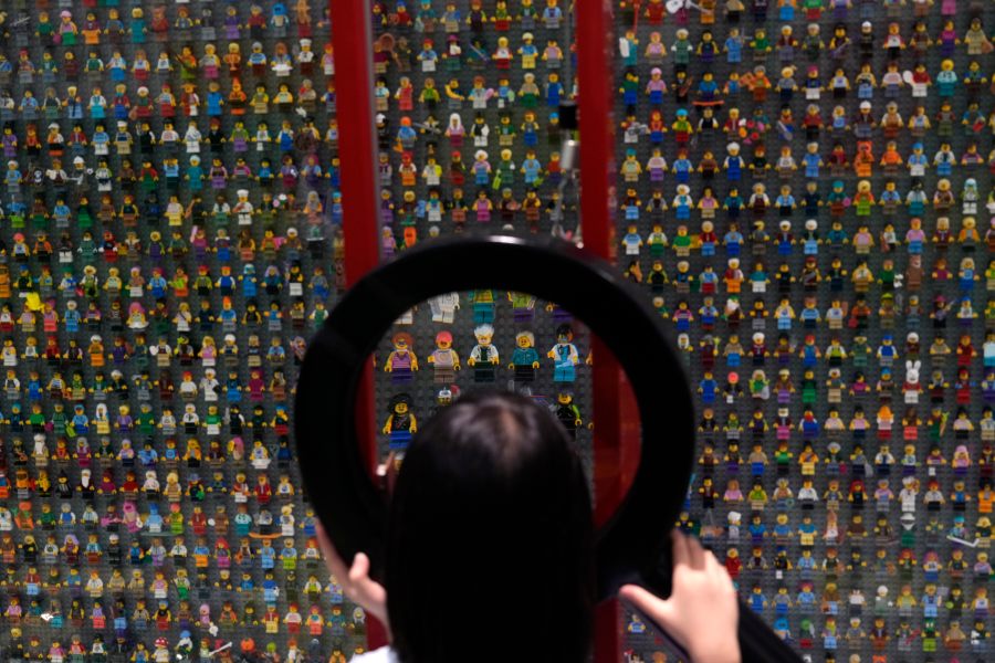 A child uses a magnifying glass to look at Lego characters at the hotel in Legoland Shanghai a day before it opens to the public in Shanghai, China, Friday, July 4, 2025. (AP Photo/Ng Han Guan)