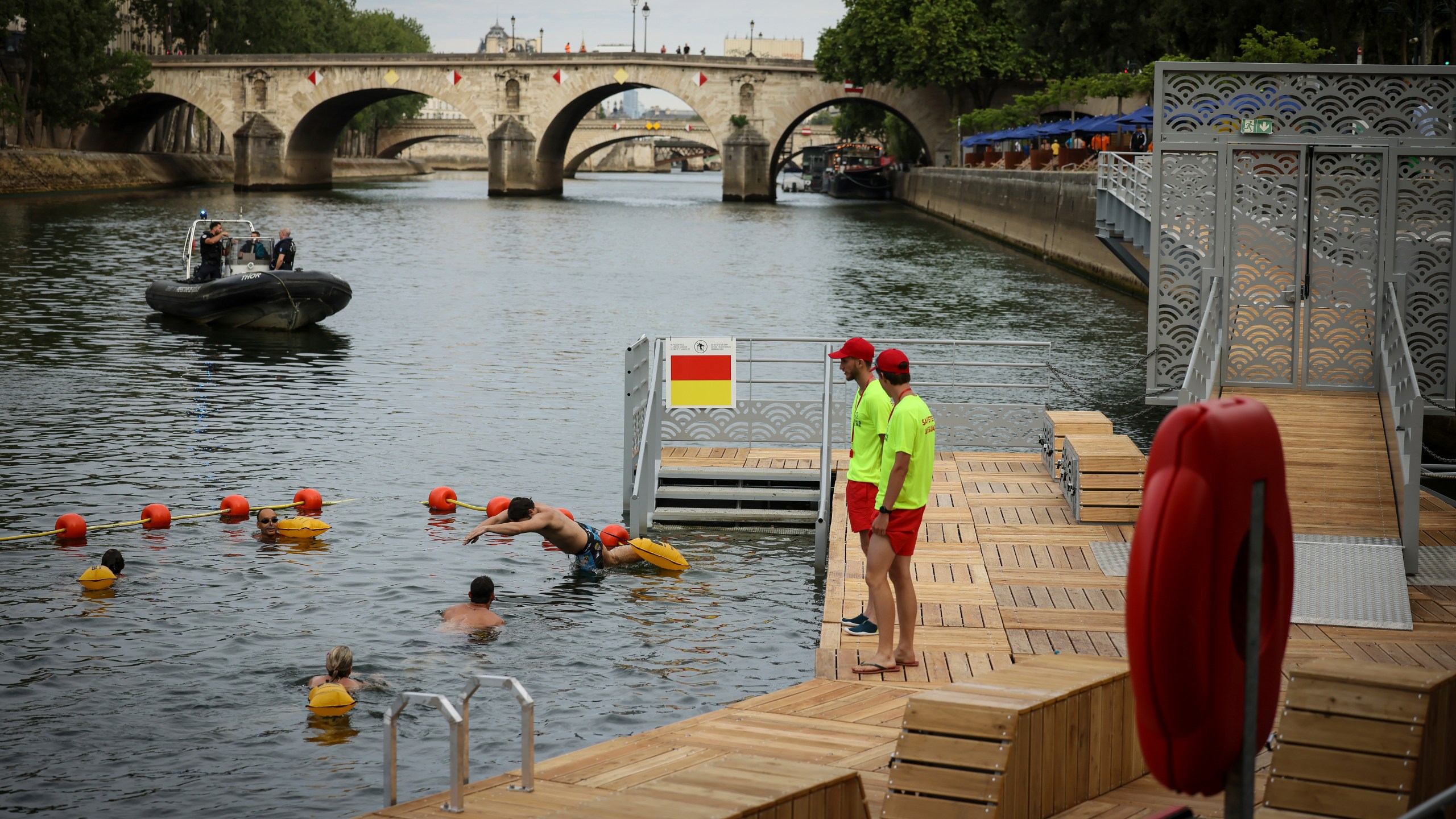 A swimmer dives in the water as people swim at the Pont Marie safe bathing site on the Seine river in Paris, France, Saturday, July 5, 2025, during the opening of the three Seine swimming pools, as part of the 'Paris Plages' event. (AP Photo/Thomas Padilla)