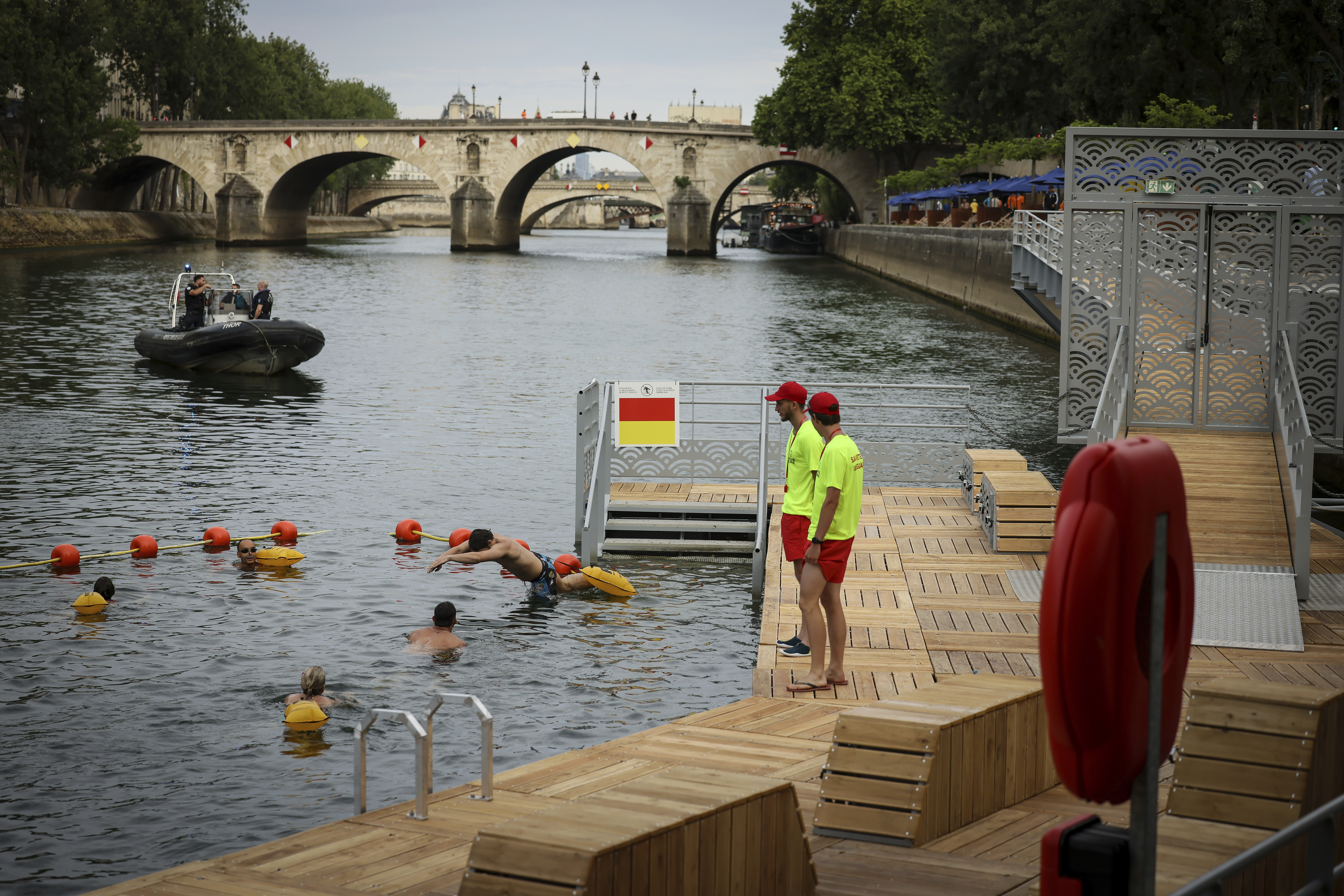 A swimmer dives in the water as people swim at the Pont Marie safe bathing site on the Seine river in Paris, France, Saturday, July 5, 2025, during the opening of the three Seine swimming pools, as part of the 'Paris Plages' event. (AP Photo/Thomas Padilla)