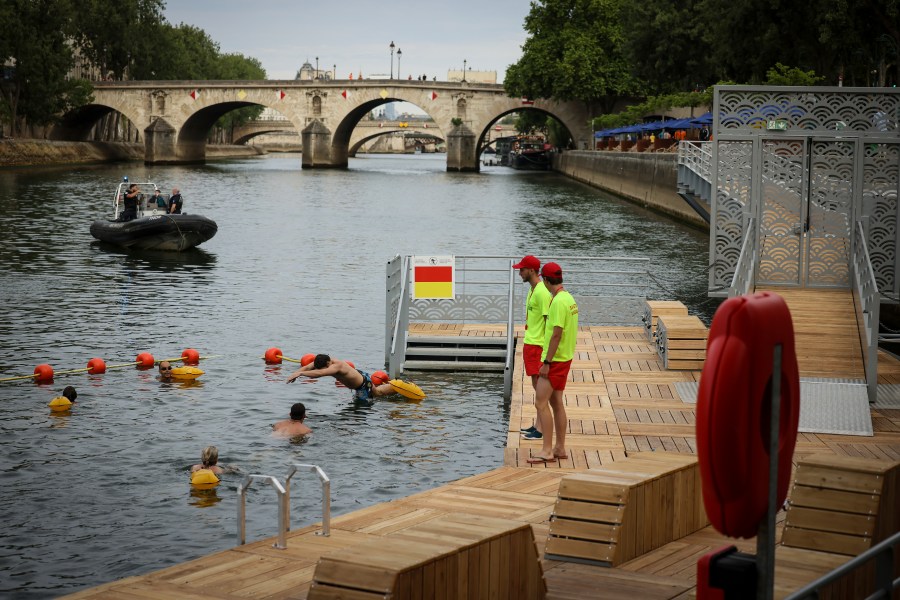 A swimmer dives in the water as people swim at the Pont Marie safe bathing site on the Seine river in Paris, France, Saturday, July 5, 2025, during the opening of the three Seine swimming pools, as part of the 'Paris Plages' event. (AP Photo/Thomas Padilla)