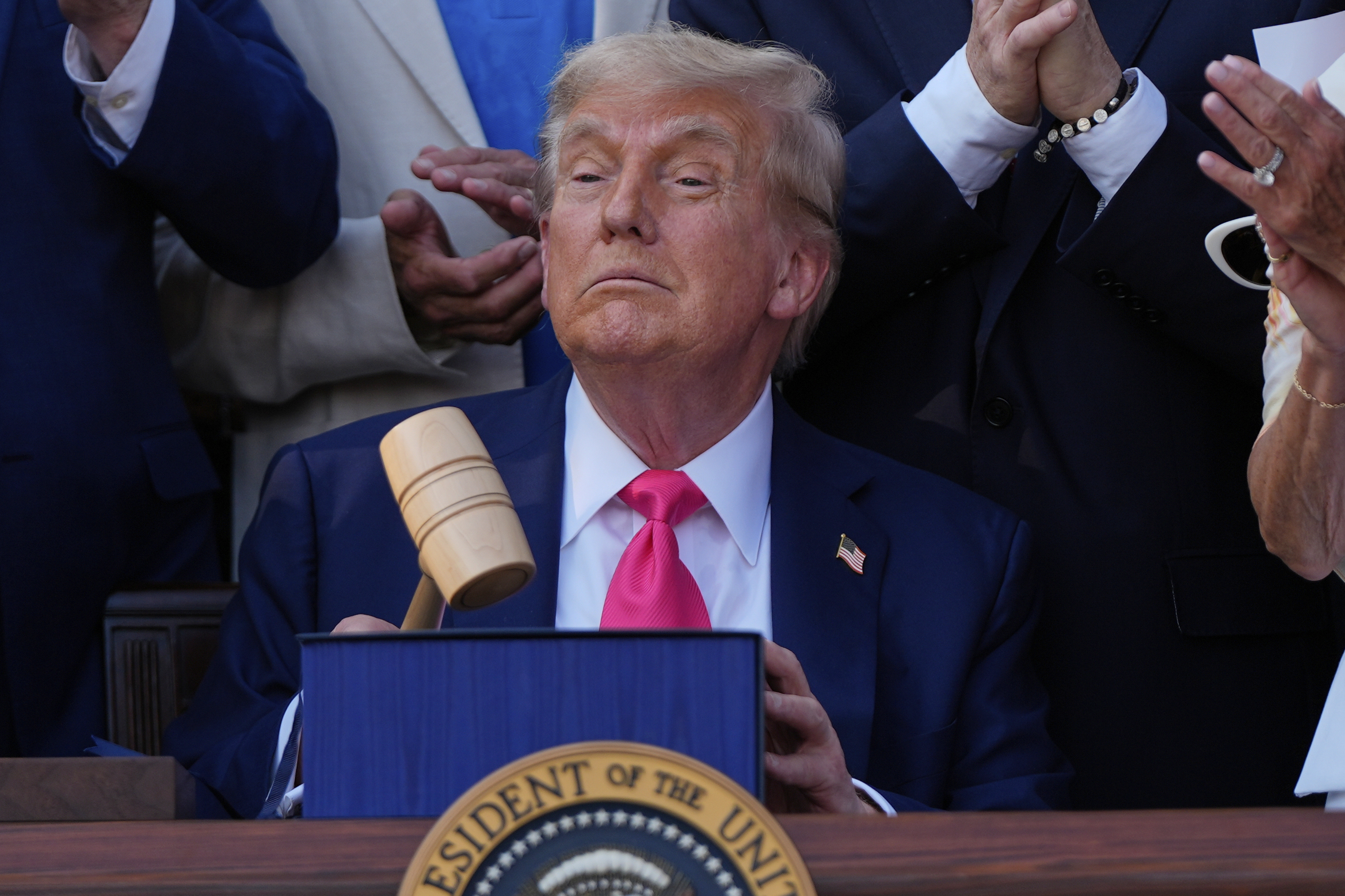 President Donald Trump holds a gavel after he signed his signature bill of tax breaks and spending cuts at the White House, Friday, July 4, 2025, in Washington, surrounded by members of Congress. (AP Photo/Julia Demaree Nikhinson)