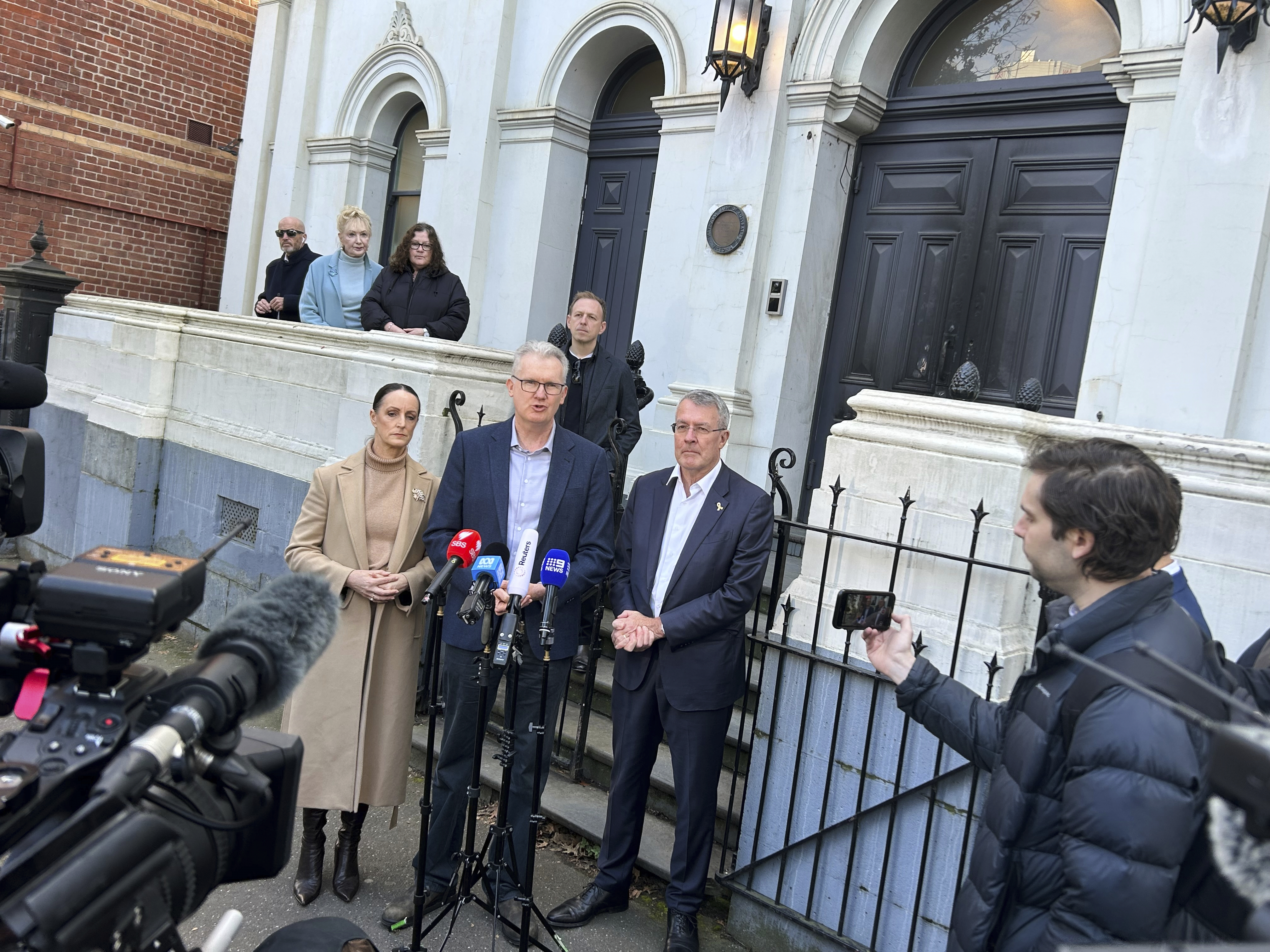 Australian government lawmaker Sarah Witty, center left, Home Affairs Minister Tony Burke, center, and Jewish government lawmaker Mark Dreyfus, center right, address the media outside the East Melbourne Synagogue in Melbourne, Australia Sunday, July 6, 2025, after someone set fire to the synagogue's front door two days earlier. (AP Photo/Rod McGuirk)