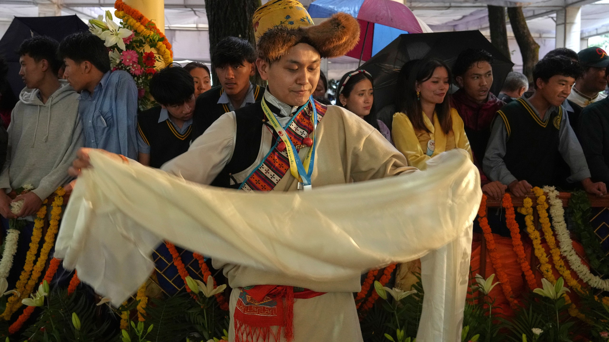 A devotees in her traditional dress folds a ceremonial offering brought for Tibetan spiritual leader the Dalai Lama while waiting for his arrival at an event celebrating his 90th birthday in Dharamshala, India, Sunday, July 6, 2025. (AP Photo/Ashwini Bhatia)