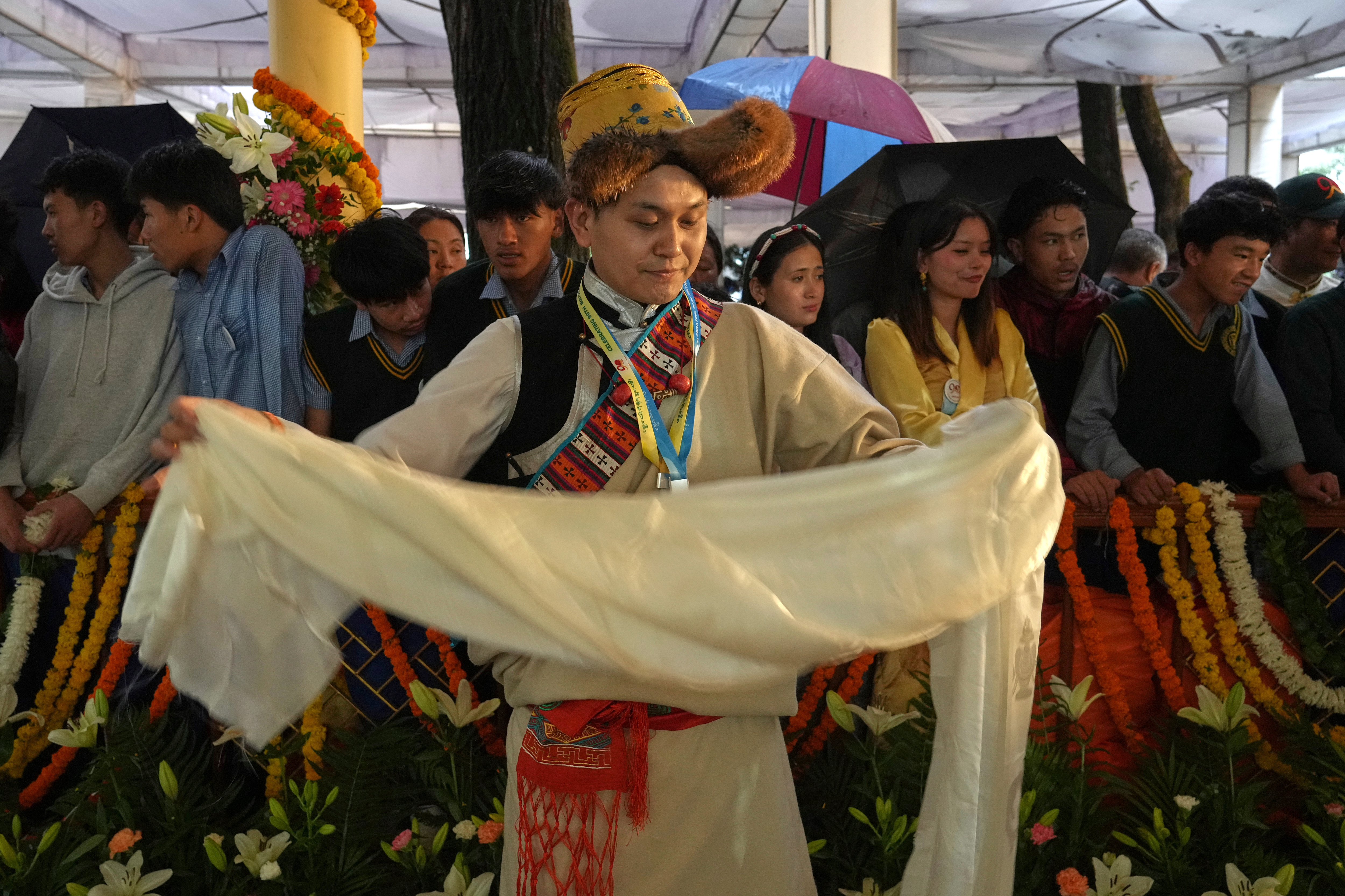 A devotees in her traditional dress folds a ceremonial offering brought for Tibetan spiritual leader the Dalai Lama while waiting for his arrival at an event celebrating his 90th birthday in Dharamshala, India, Sunday, July 6, 2025. (AP Photo/Ashwini Bhatia)