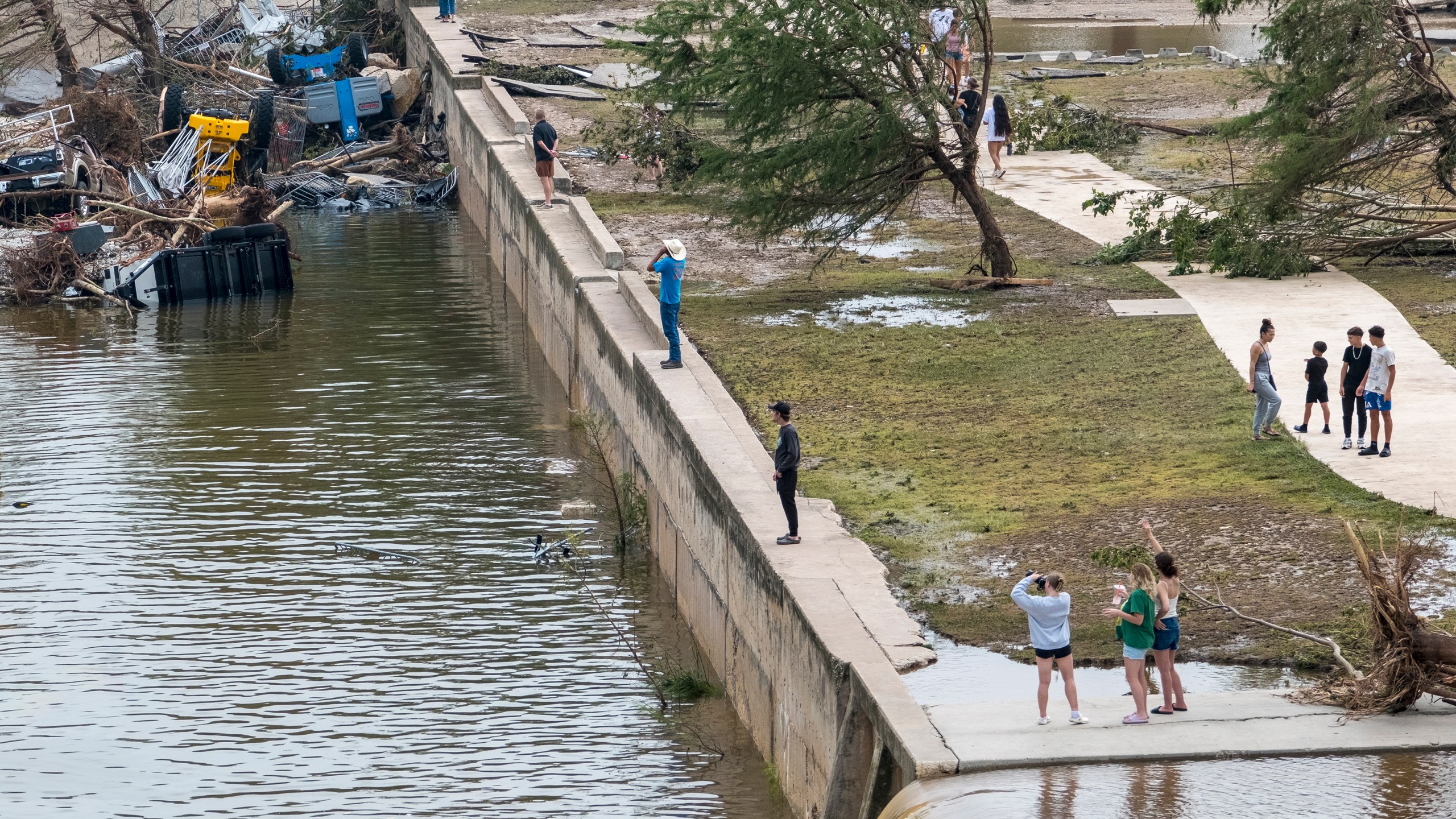 Onlookers walk along the banks of the Guadalupe River in Louise Hays Park, Saturday, July 5, 2025, in Kerrville, Texas. (AP Photo/Rodolfo Gonzalez)