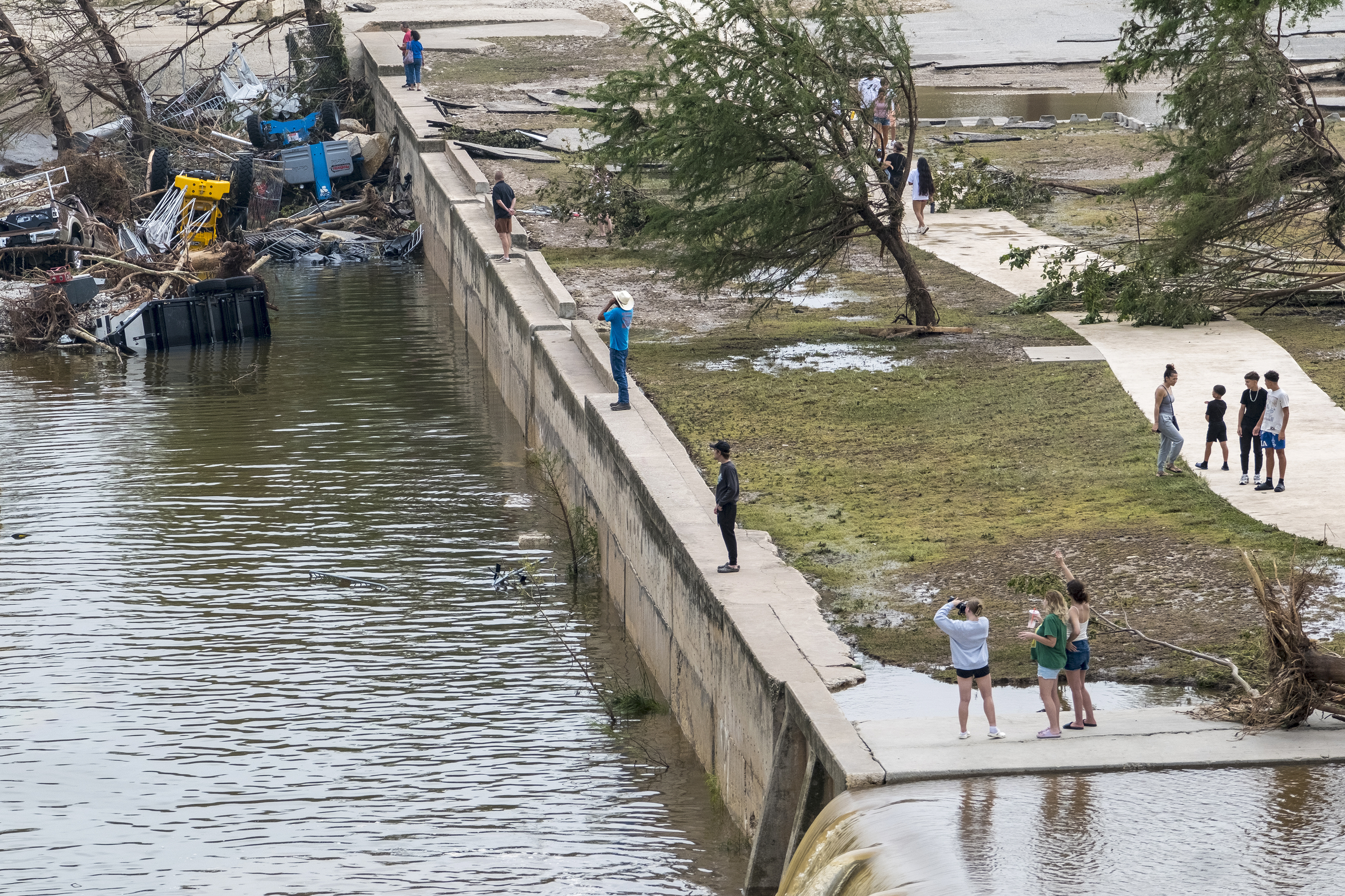 Onlookers walk along the banks of the Guadalupe River in Louise Hays Park, Saturday, July 5, 2025, in Kerrville, Texas. (AP Photo/Rodolfo Gonzalez)