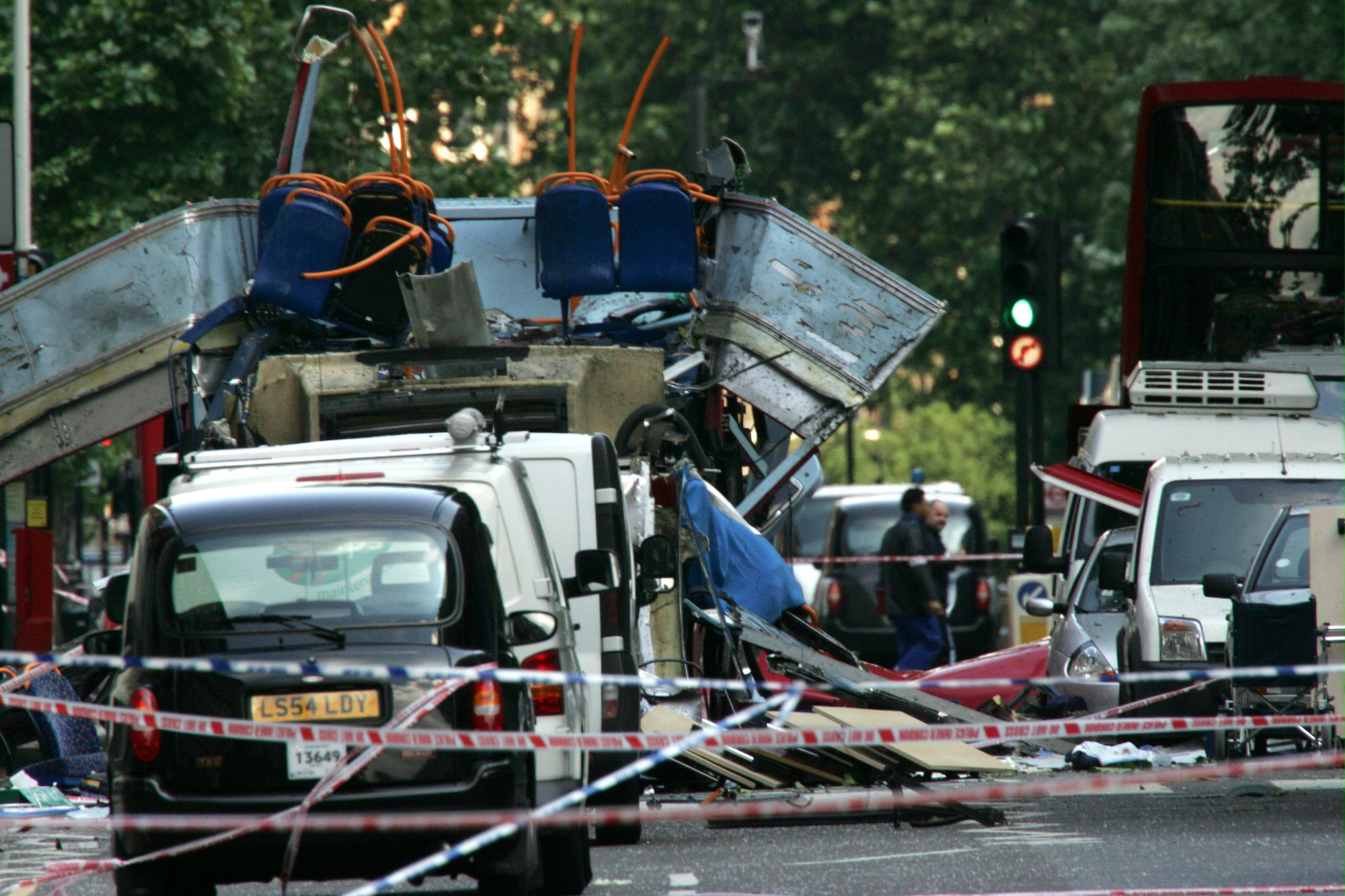 FILE - The wreckage of a double-decker bus with its top blown off by a bomb and damaged cars scattered on the road at Tavistock Square in central London, July 7, 2005. (AP Photo/Sang Tan, File)