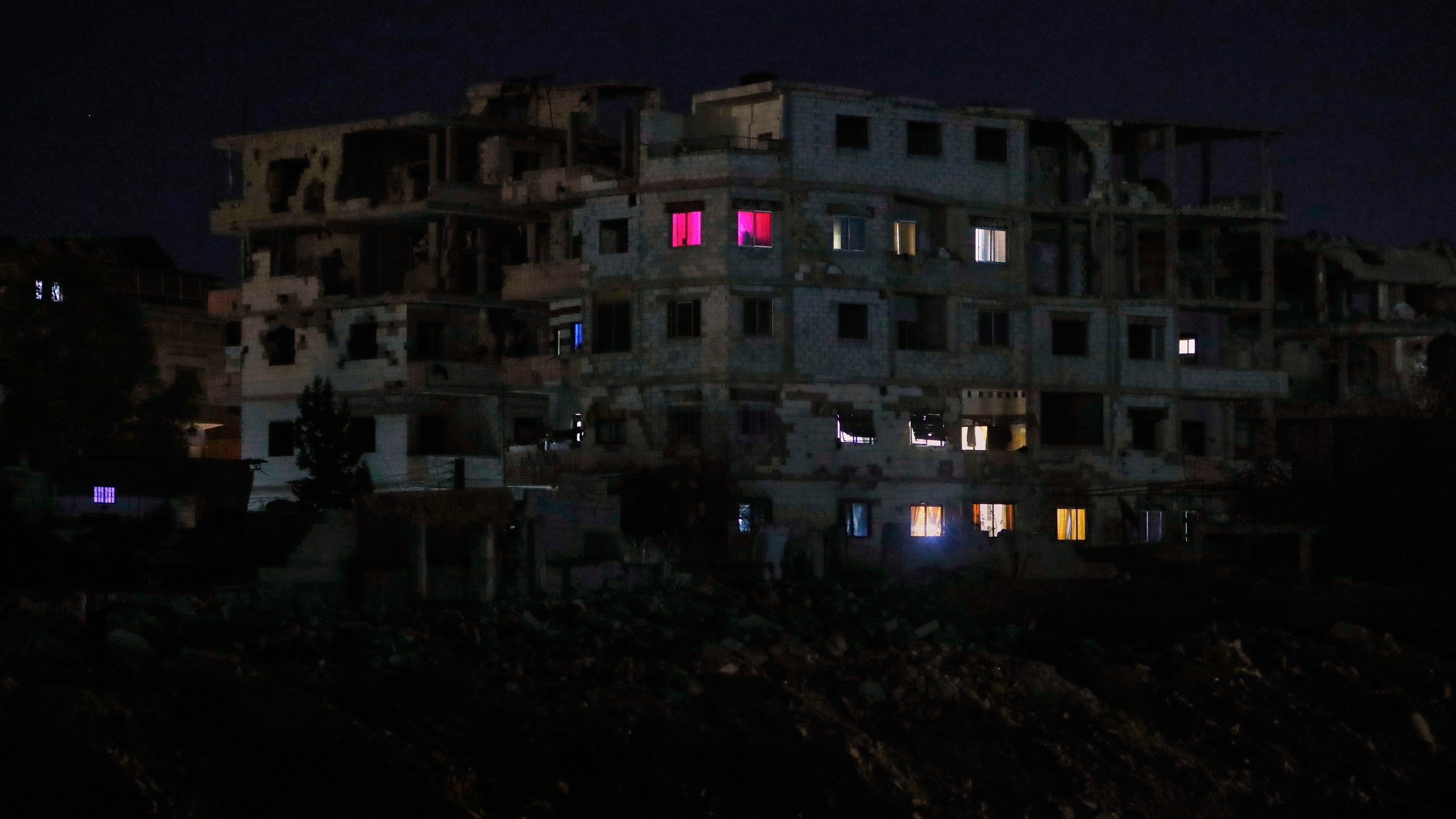 FILE - Lights illuminate a few windows of a damaged building in Damascus, Syria, early Thursday, March 27, 2025. (AP Photo/Omar Sanadiki, File)
