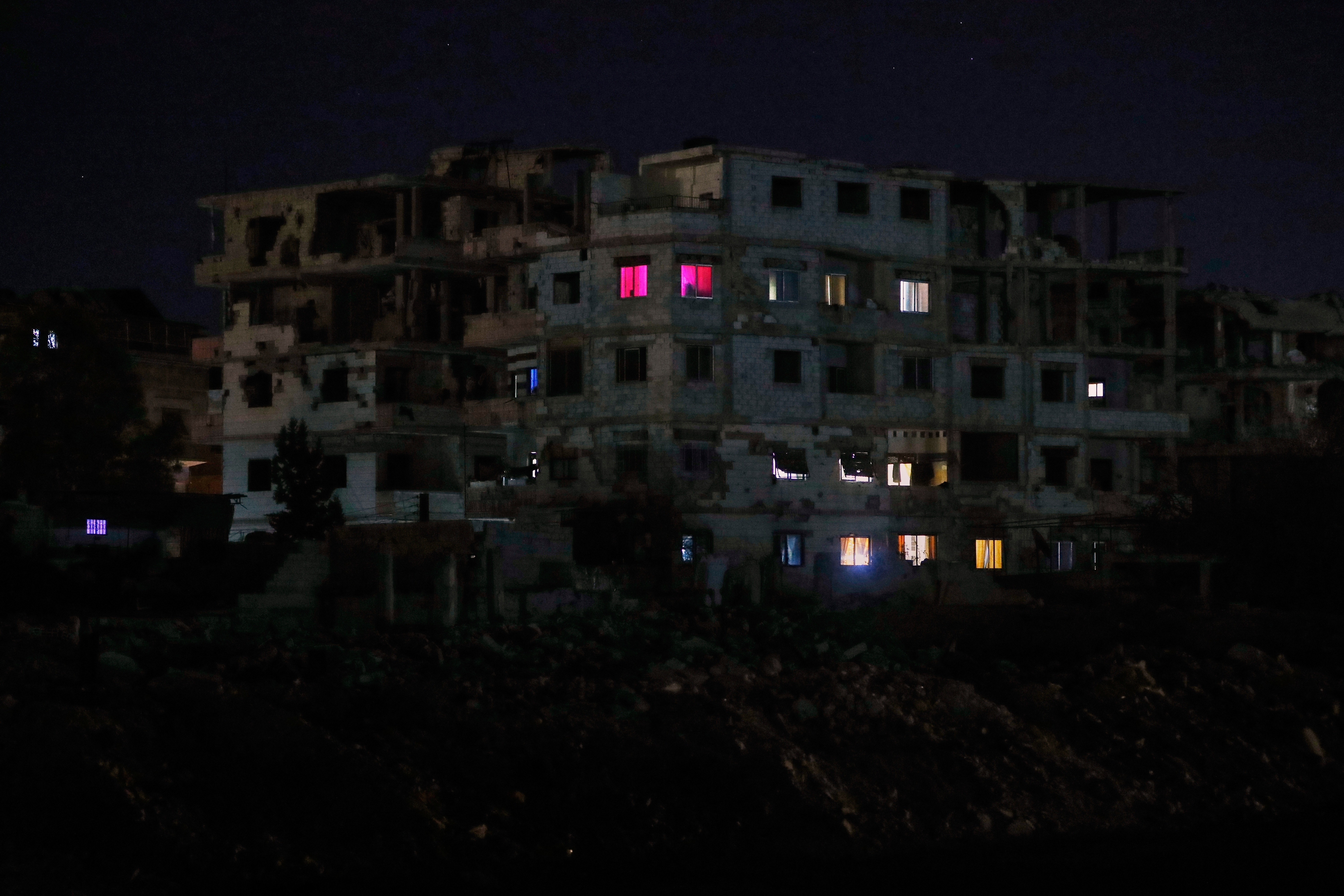 FILE - Lights illuminate a few windows of a damaged building in Damascus, Syria, early Thursday, March 27, 2025. (AP Photo/Omar Sanadiki, File)