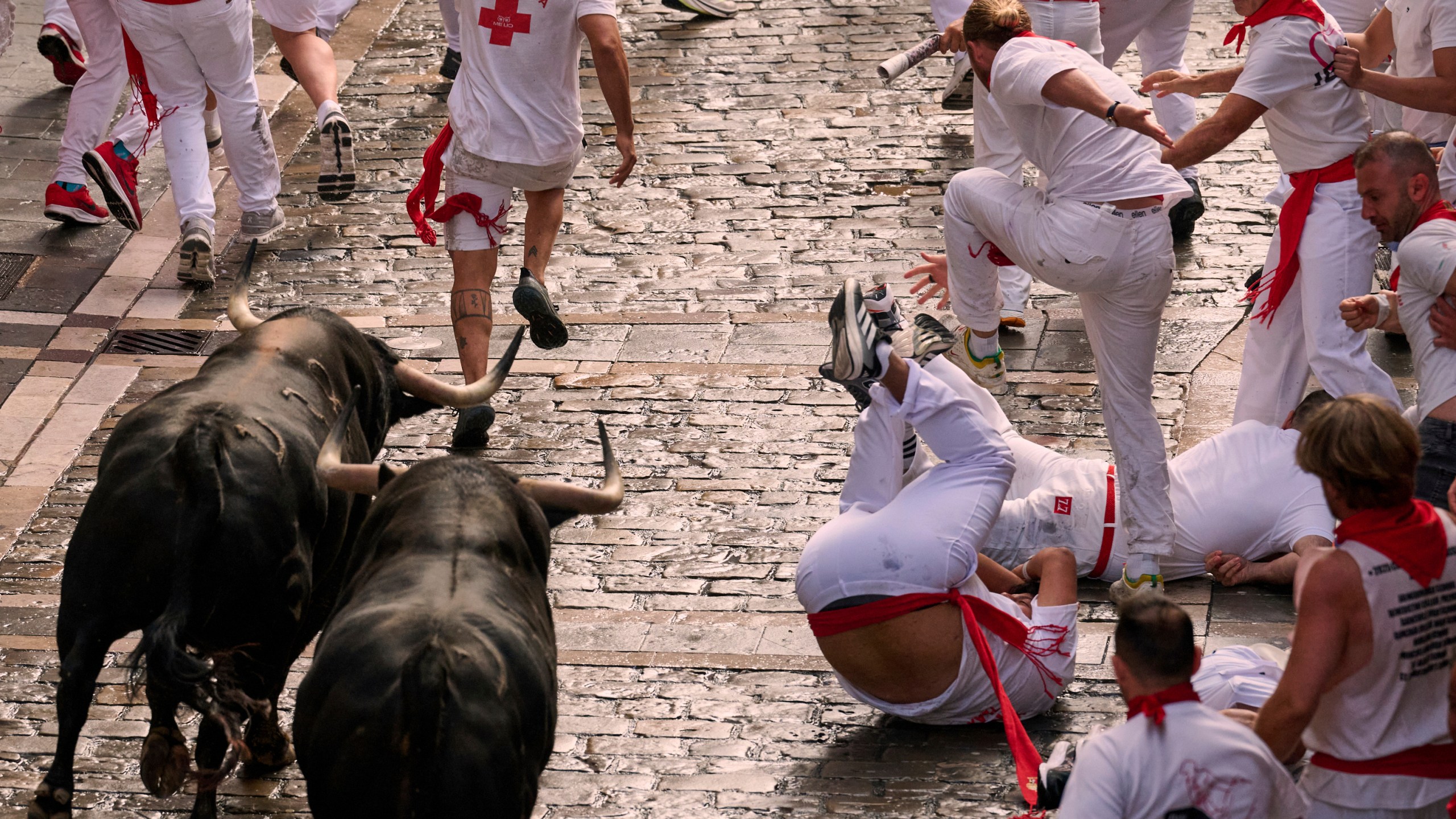 Revelers run with bulls from Fuente Ymbro ranch during the first day of the running of the bulls at the San Fermín fiestas in Pamplona, Spain, Monday, July 7, 2025. (AP Photo/Miguel Oses)