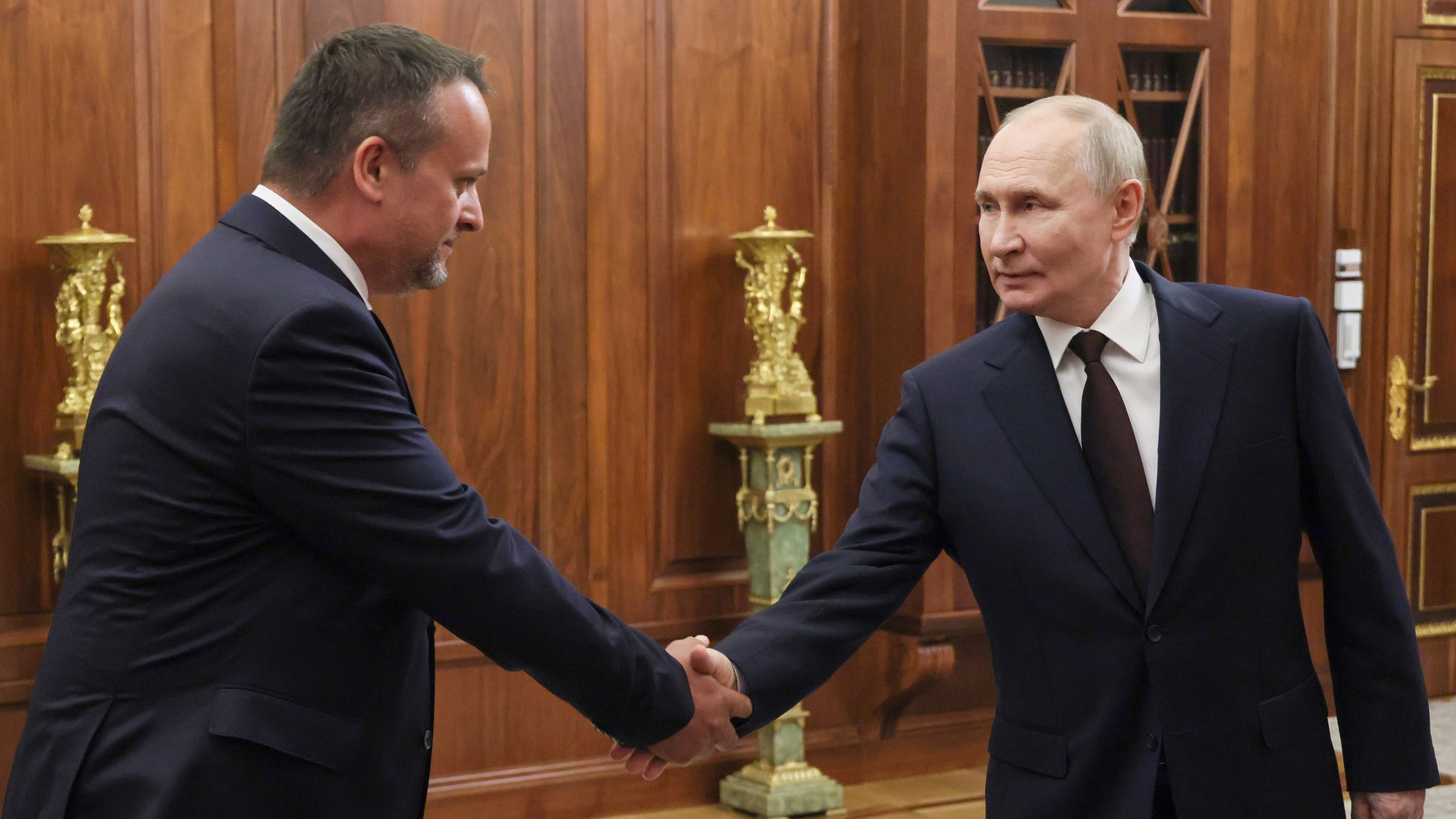 Russian President Vladimir Putin, right, shakes hands with a newly appointed acting Transport Minister Andrey Nikitin during their meeting at the Kremlin in Moscow, Russia, Monday, July 7, 2025. (Mikhail Metzel, Sputnik, Kremlin Pool Photo via AP)