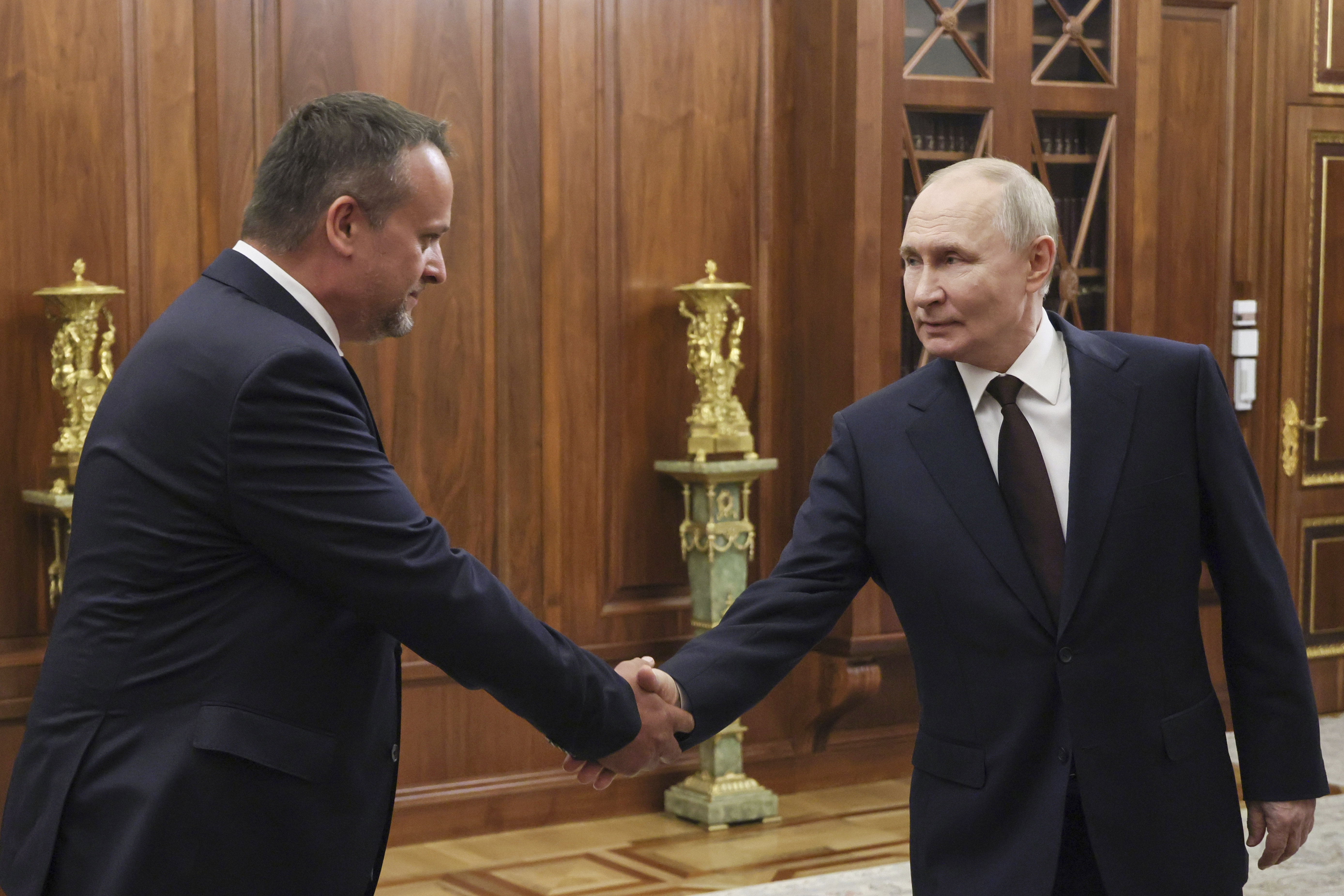 Russian President Vladimir Putin, right, shakes hands with a newly appointed acting Transport Minister Andrey Nikitin during their meeting at the Kremlin in Moscow, Russia, Monday, July 7, 2025. (Mikhail Metzel, Sputnik, Kremlin Pool Photo via AP)