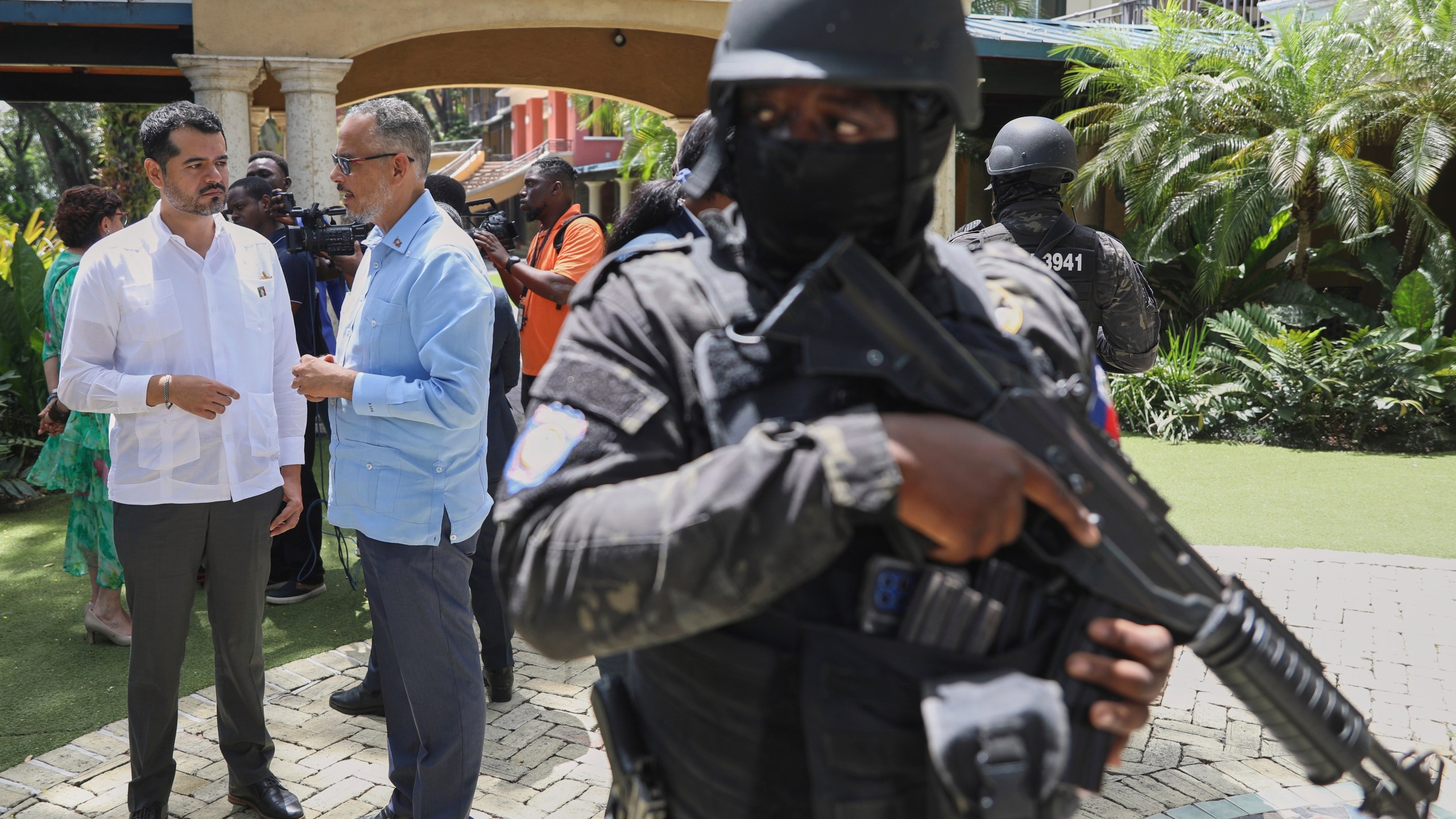 Security guards stand watch as Haiti's Prime Minister Alix Didier Fils-Aime, center, talks with the Mexico's Charge d'Affaires Jesus Cisneros after attending an event marking one year since the start of the Multinational Security Support Mission in Port-au-Prince, Haiti, Thursday, June 26, 2025. (AP Photo/Odelyn Joseph)