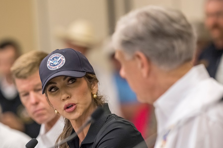 CORRECTS TO KERRVILLE, NOT INGRAM - Homeland Security Secretary Kristi Noem, center, speaks with Texas Gov. Greg Abbott, right, about ongoing search and rescue efforts after recent flooding along the Guadalupe River during a press conference on Saturday, July 5, 2025, in Kerrville, Texas. (AP Photo/Rodolfo Gonzalez)