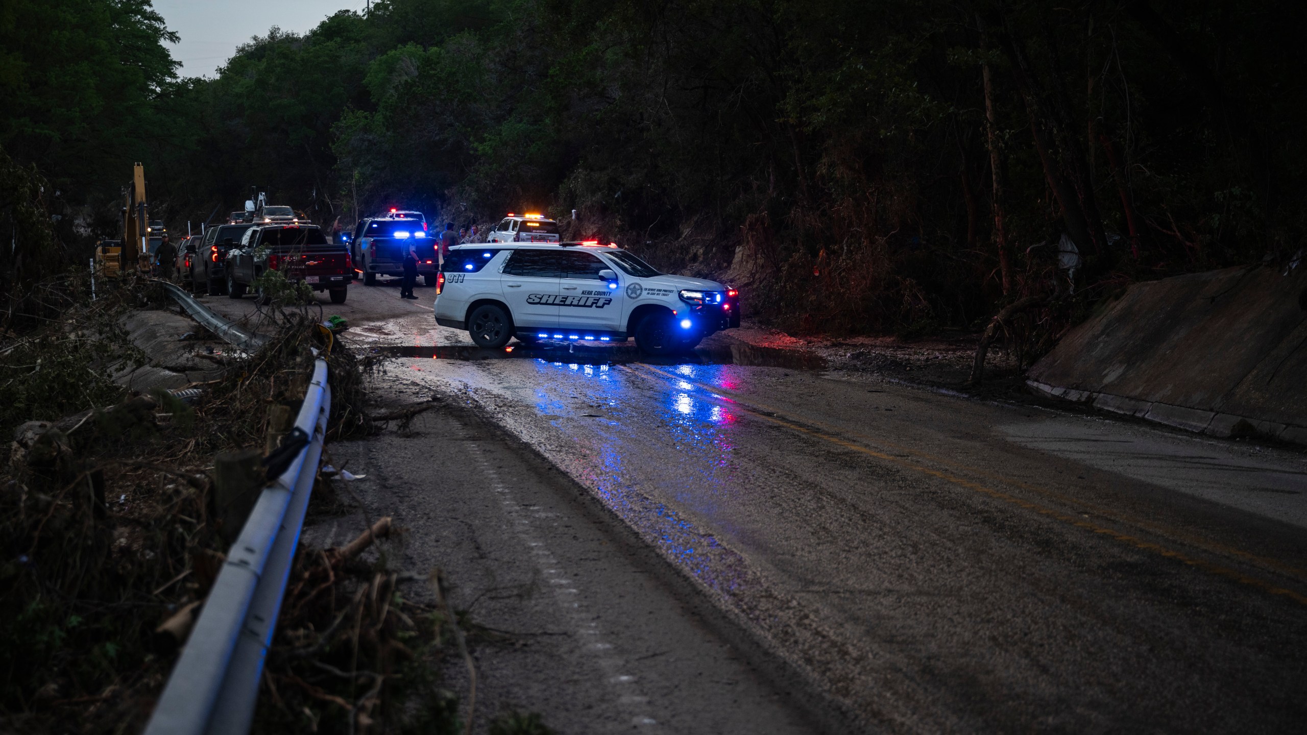 Law enforcement officials block a road along the Guadalupe River as they load an extricated body into the back of a pickup truck in Hunt, Texas, Monday, July 7, 2025, after a flash flood swept through the area. (AP Photo/Eli Hartman)
