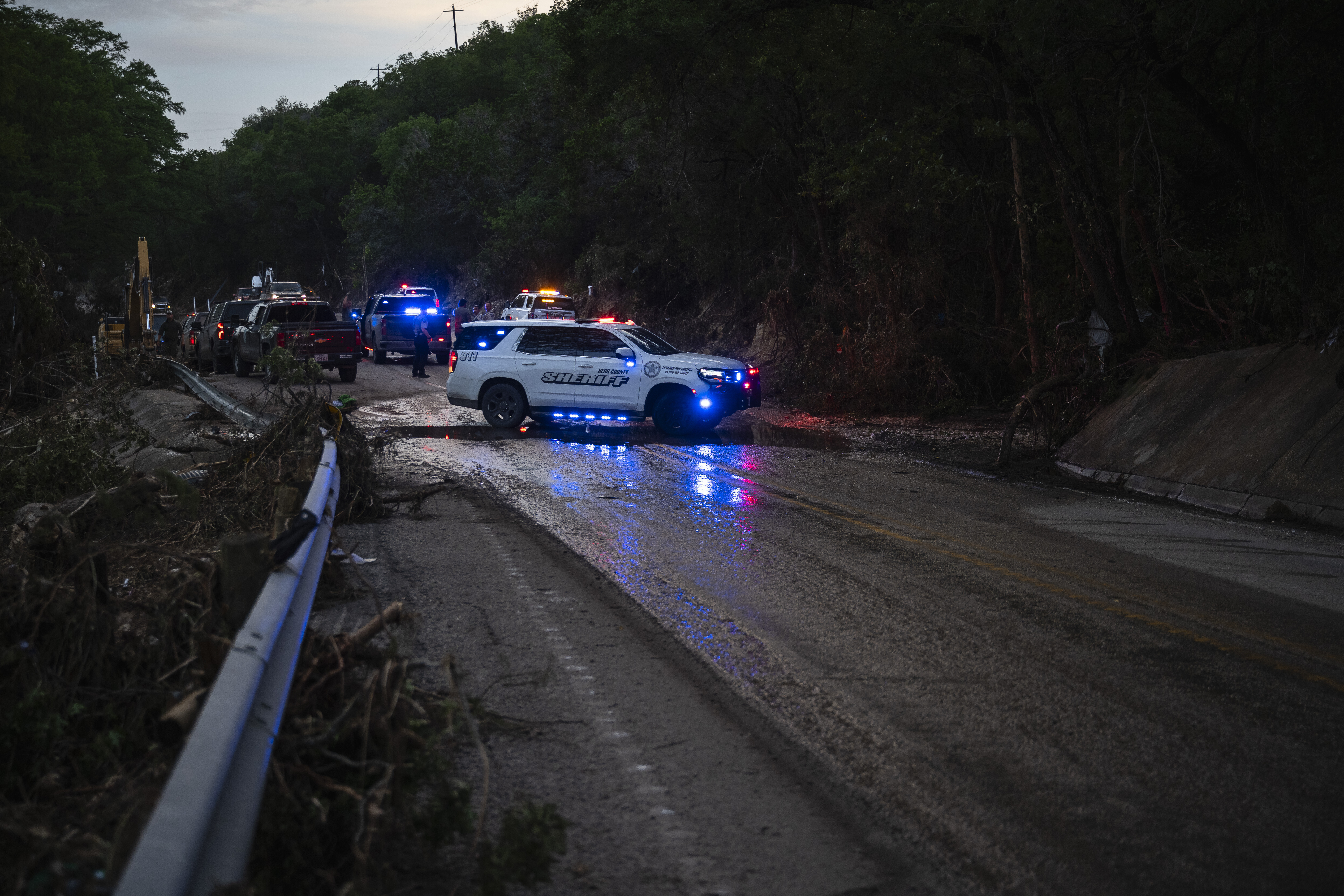 Law enforcement officials block a road along the Guadalupe River as they load an extricated body into the back of a pickup truck in Hunt, Texas, Monday, July 7, 2025, after a flash flood swept through the area. (AP Photo/Eli Hartman)