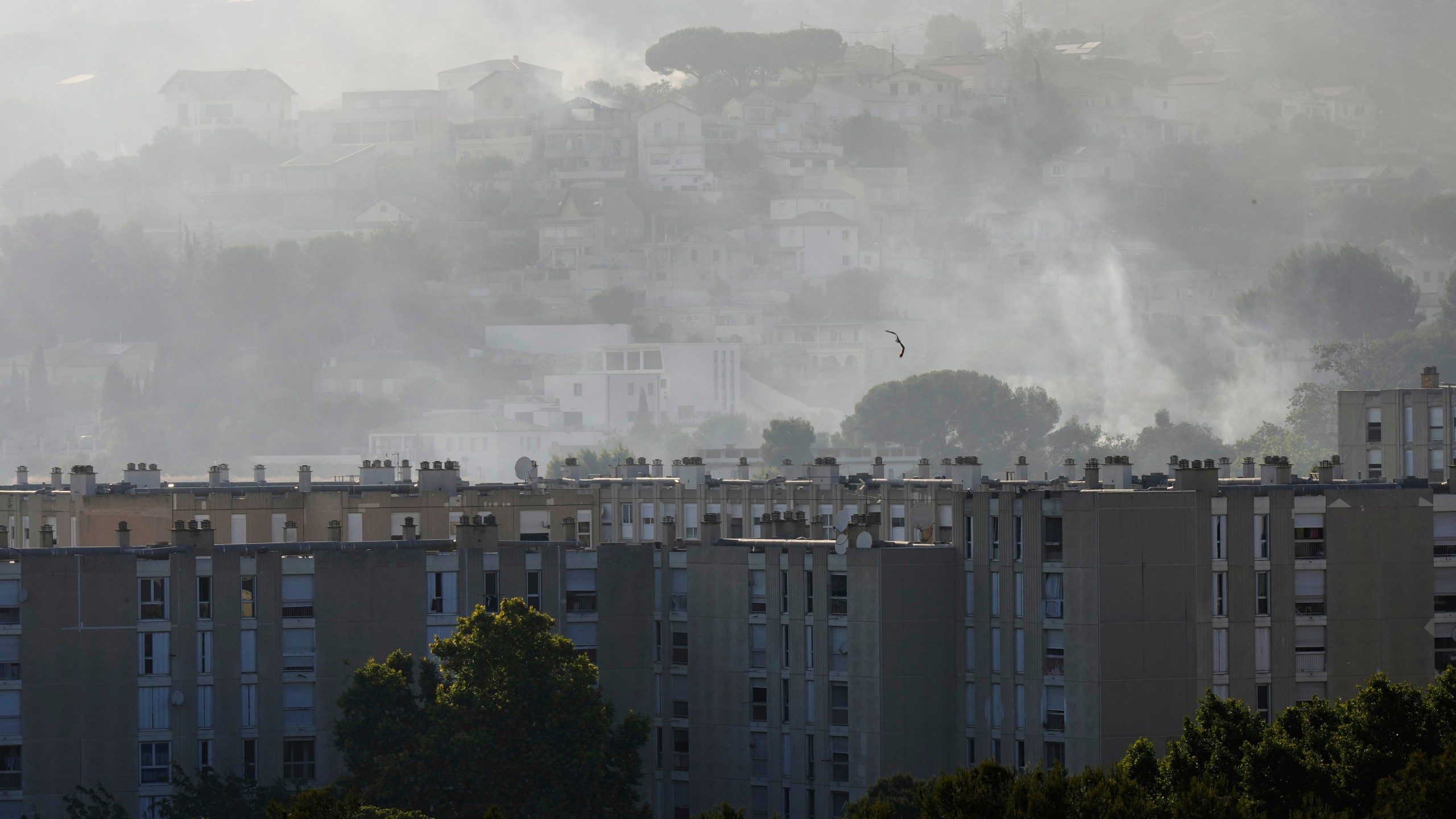 CORRECTS TO CASTELLANE, NOT CATELLANE - Smoke rises behind buildings during wildfire Tuesday, July 8, 2025 in La Castellane district of Marseille, southern France. (AP Photo/Lewis Joly)