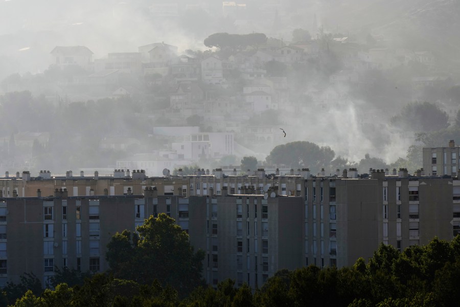 CORRECTS TO CASTELLANE, NOT CATELLANE - Smoke rises behind buildings during wildfire Tuesday, July 8, 2025 in La Castellane district of Marseille, southern France. (AP Photo/Lewis Joly)