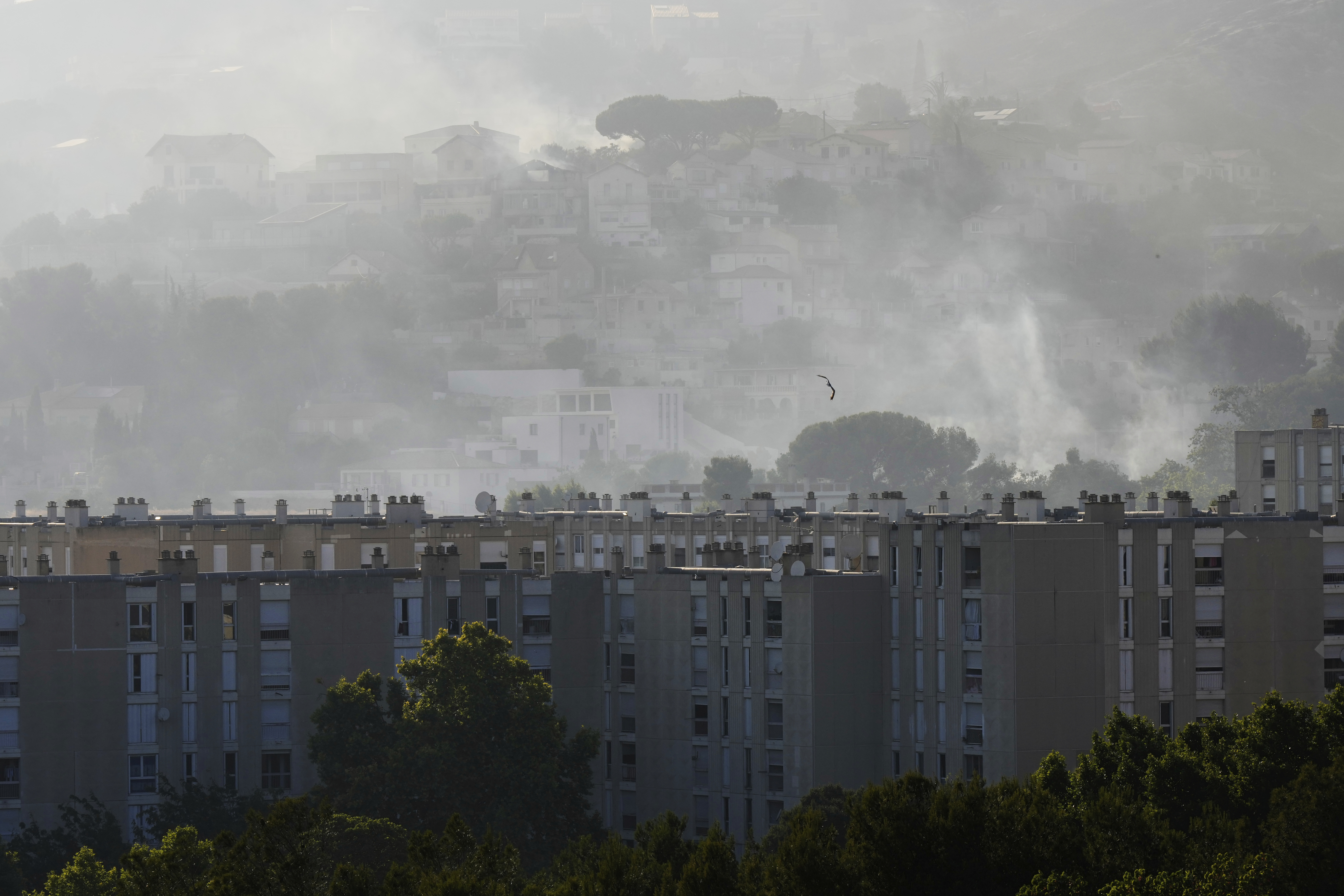 CORRECTS TO CASTELLANE, NOT CATELLANE - Smoke rises behind buildings during wildfire Tuesday, July 8, 2025 in La Castellane district of Marseille, southern France. (AP Photo/Lewis Joly)