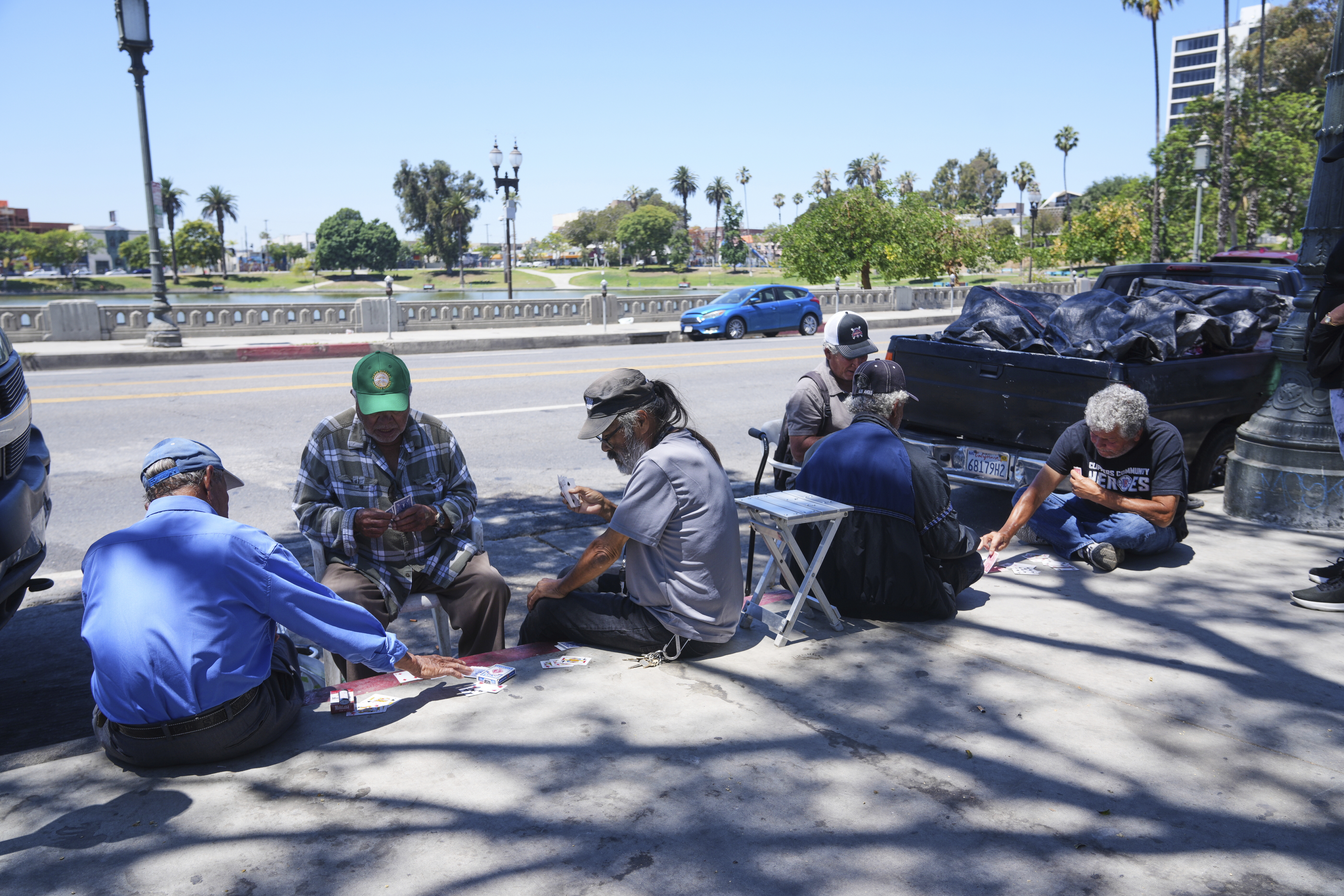 People play cards on a sidewalk at MacArthur Park, Tuesday, July 8, 2025, in Los Angeles. (AP Photo/Damian Dovarganes)