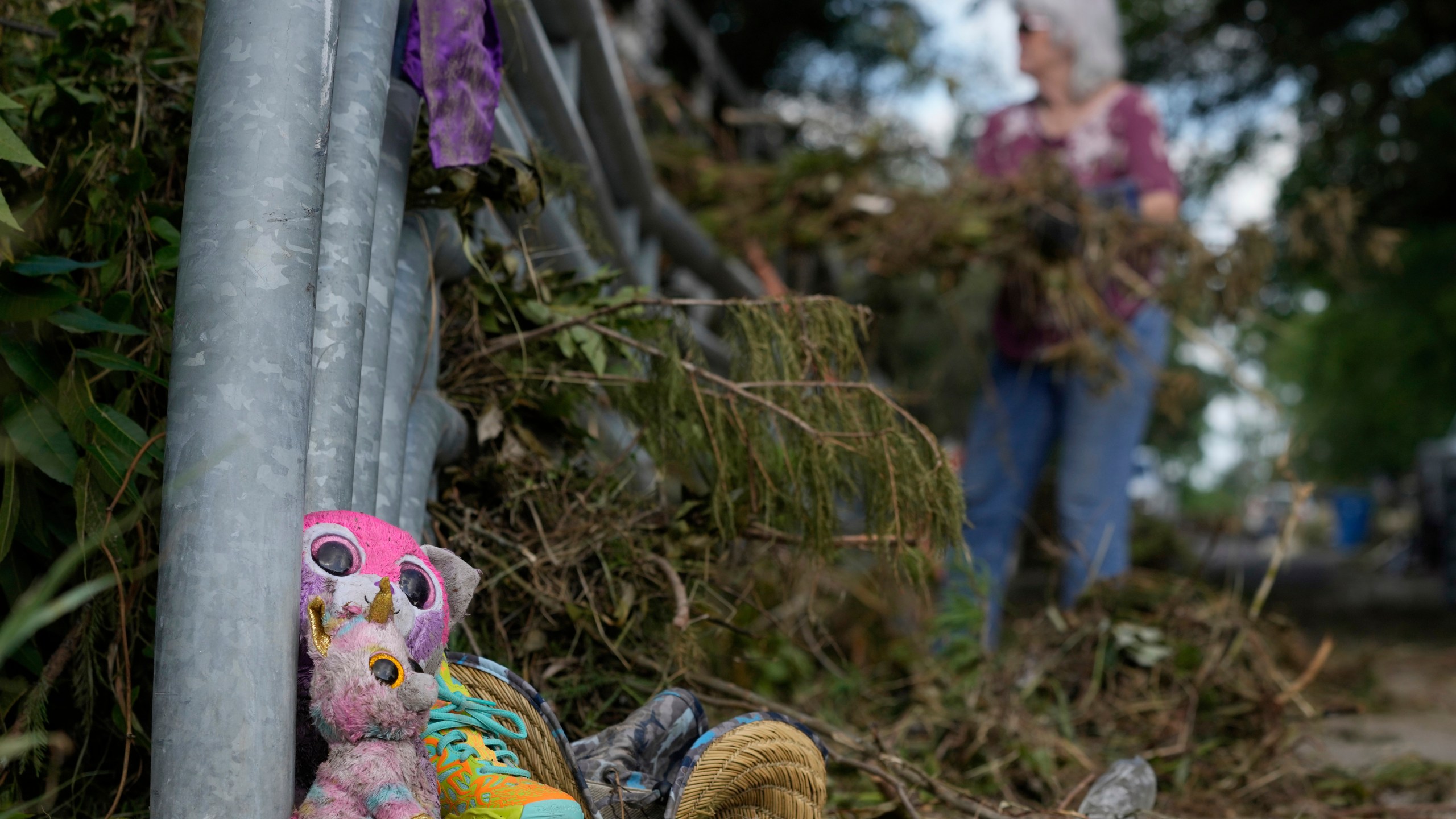Lost items sit at a bridge as a volunteer cleans up debris on Tuesday, July 8, 2025, after a flash flood swept through the area in Kerrville, Texas. (AP Photo/Ashley Landis)