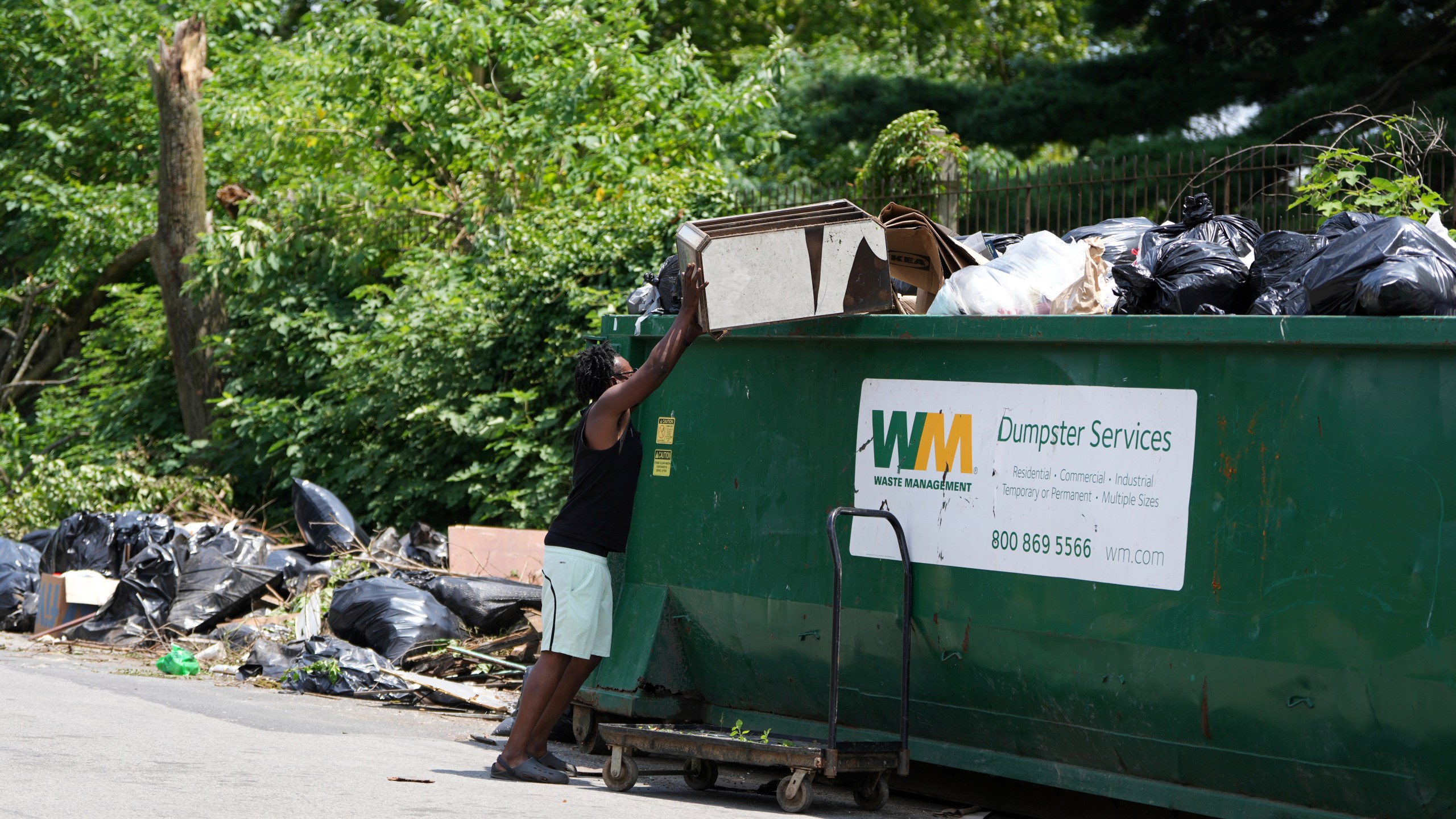 A man drops off trash at a garbage collection site, Wednesday, July 9, 2025, in Philadelphia. (AP Photo/Matt Slocum)