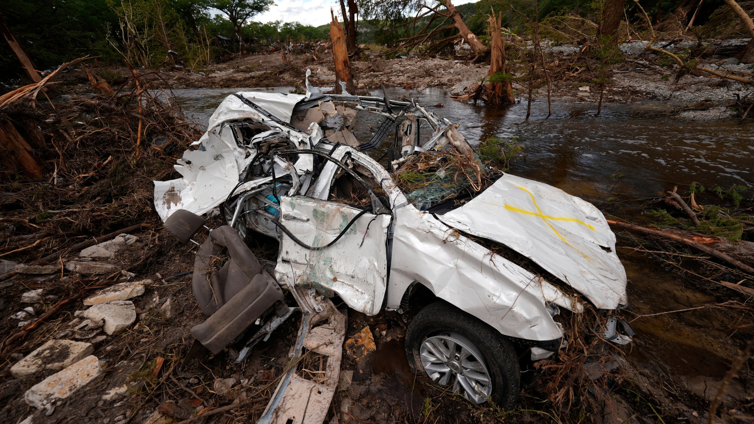 A destroyed vehicle sits next to the Guadalupe River on Wednesday, July 9, 2025, in Hunt, Texas, after a flash flood swept through the area. (AP Photo/Gerald Herbert)