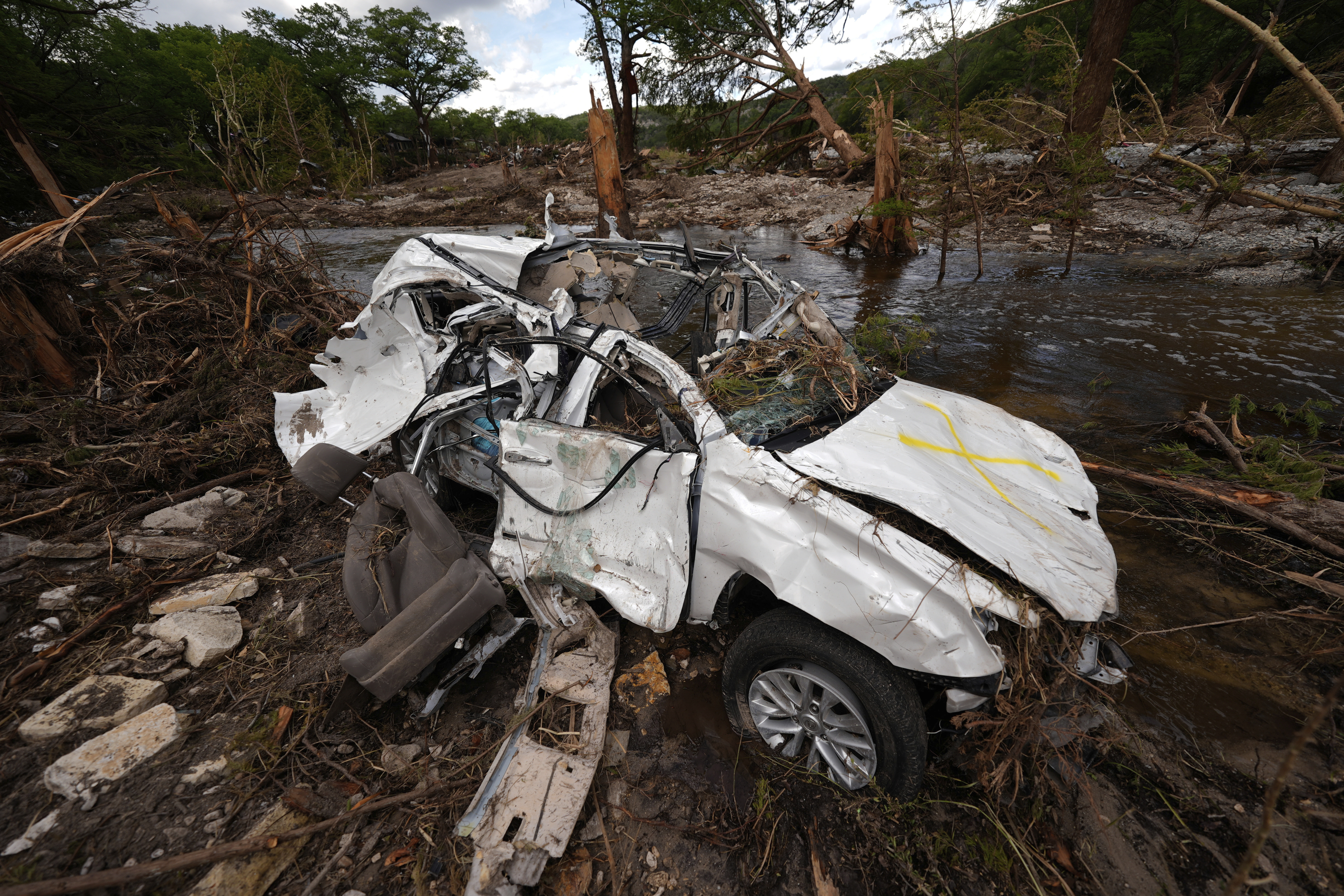 A destroyed vehicle sits next to the Guadalupe River on Wednesday, July 9, 2025, in Hunt, Texas, after a flash flood swept through the area. (AP Photo/Gerald Herbert)