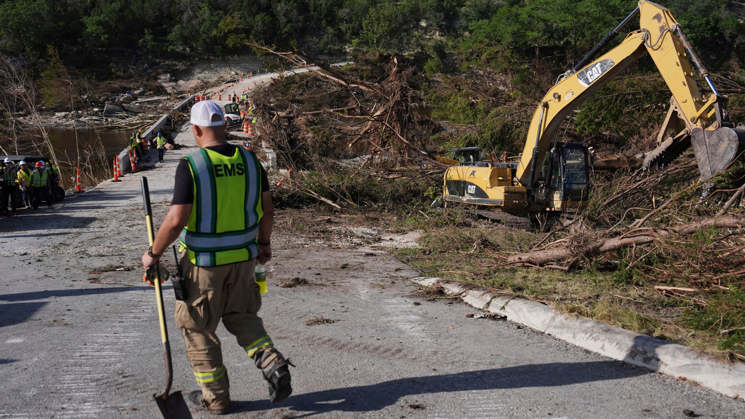 Crews work on the Cade Loop Bridge to clear debris following flooding, Thursday, July 10, 2025, in Ingram, Texas. (AP Photo/Joshua A. Bickel)